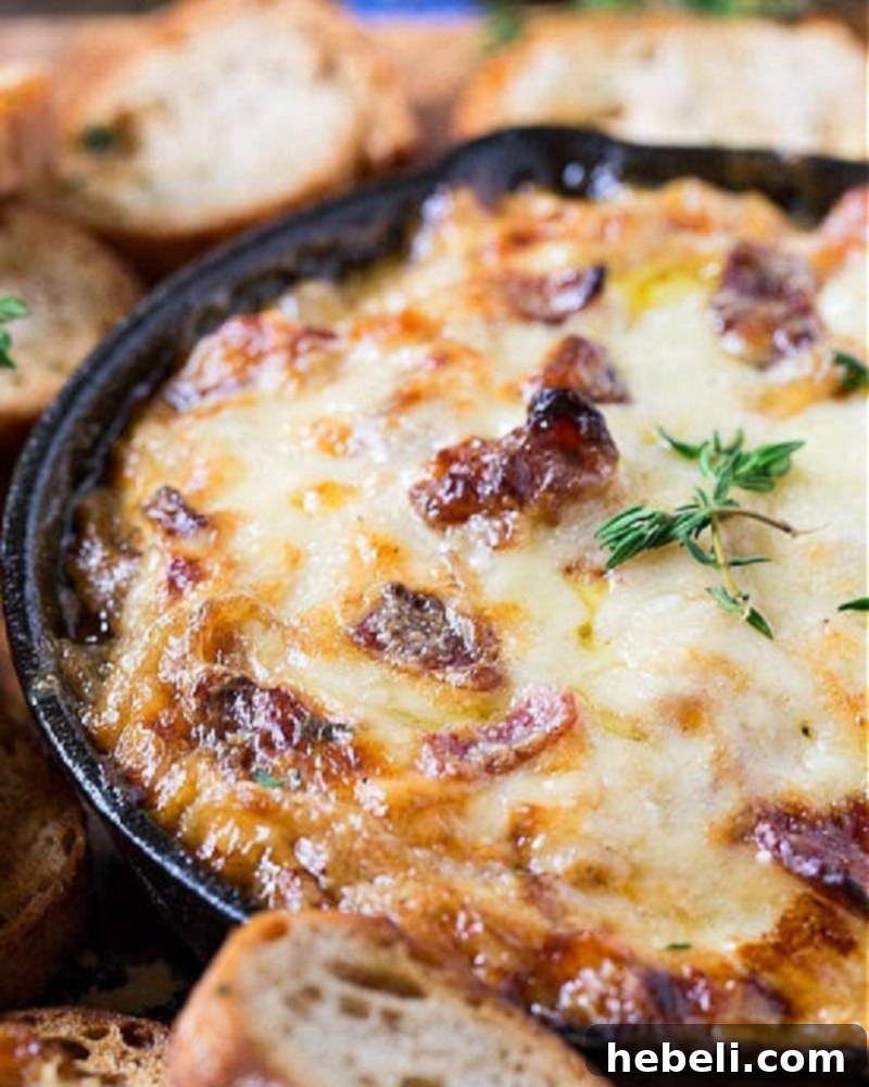 A cast iron skillet filled with bubbling Hot Caramelized Onion Dip with Bacon and Gruyere, ready to be served.