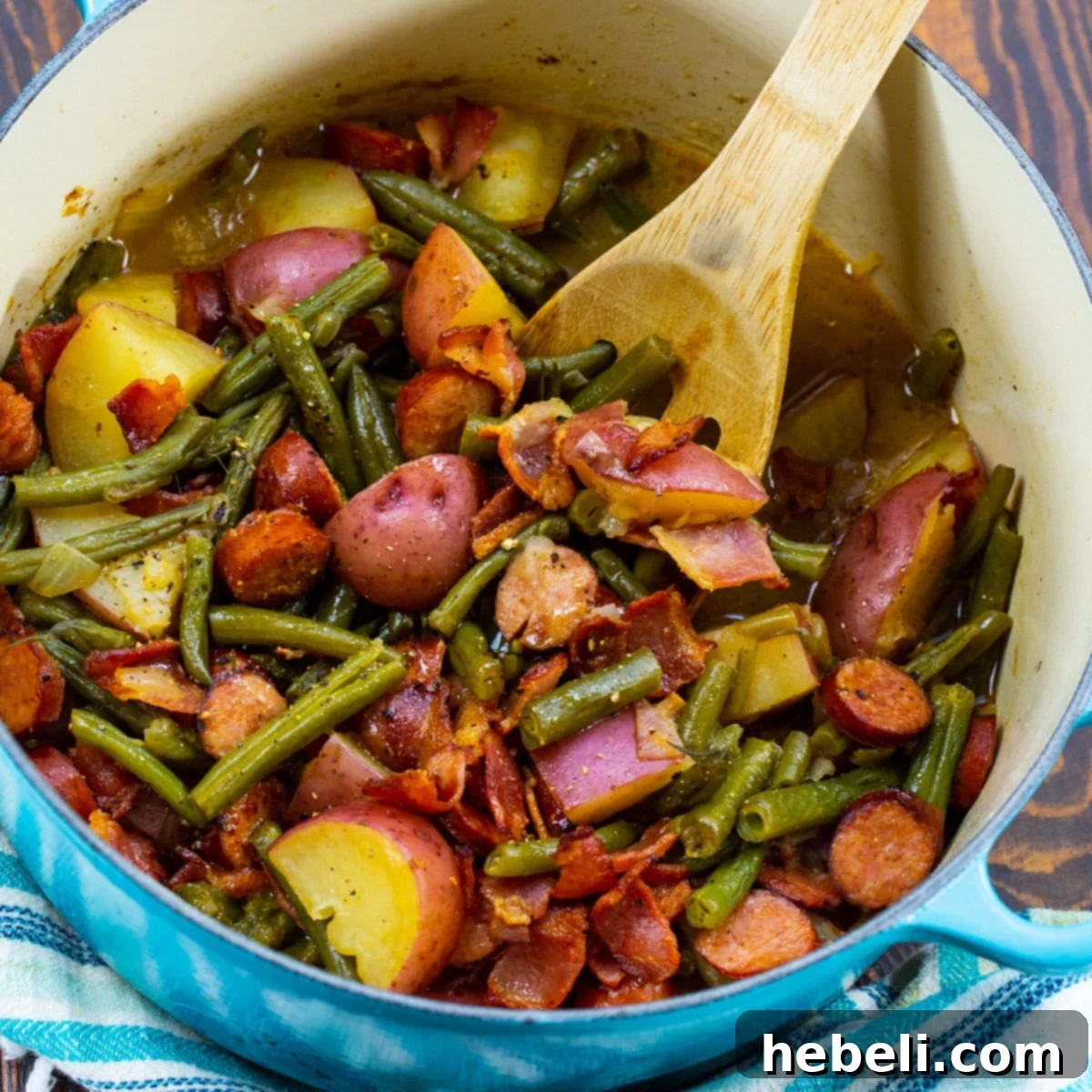 Hearty Smothered Cajun Green Beans with bacon, sausage, and potatoes in a Dutch oven, ready to serve.