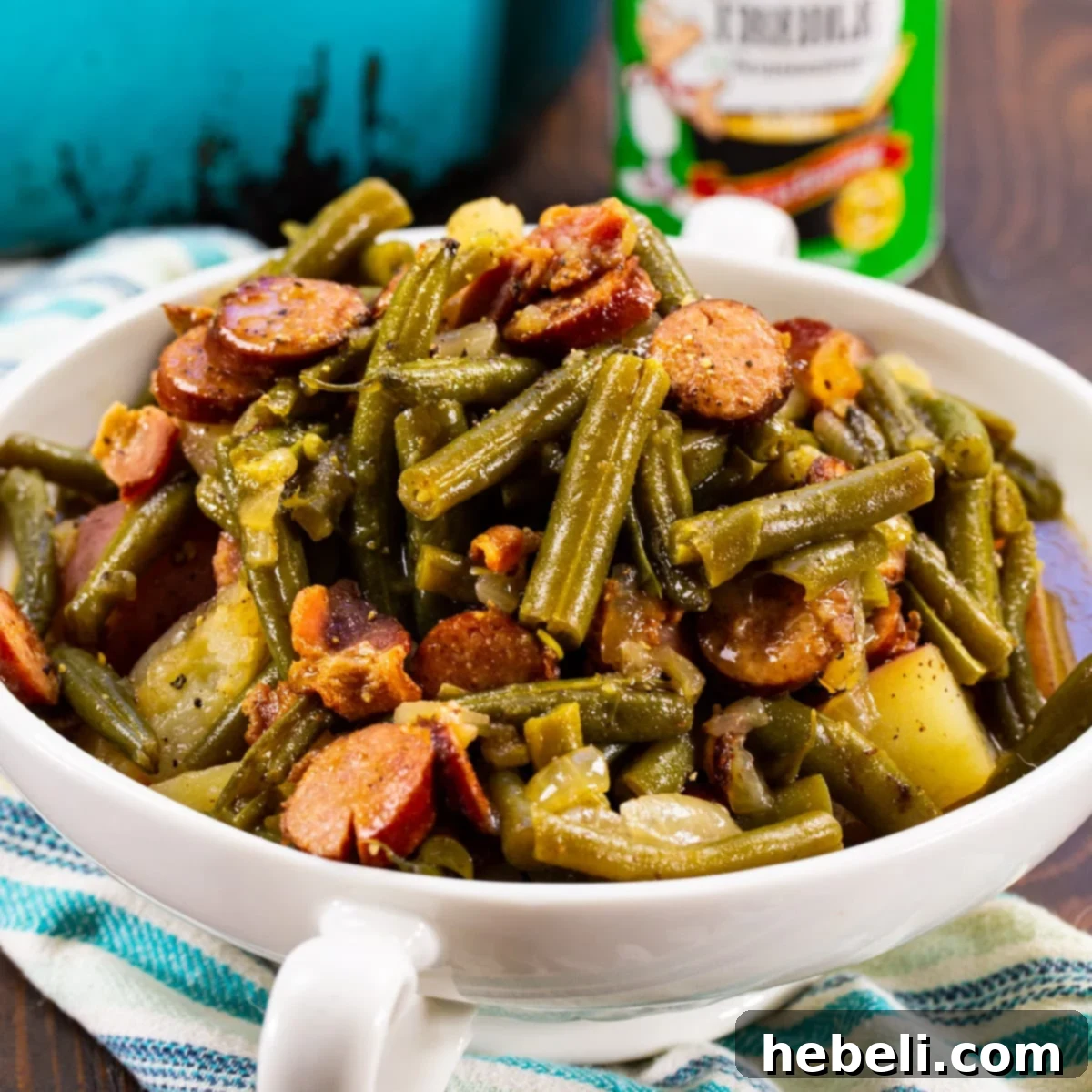 A close-up of Smothered Cajun Green Beans in a rustic serving dish, showcasing the tender beans, sausage, and potatoes.