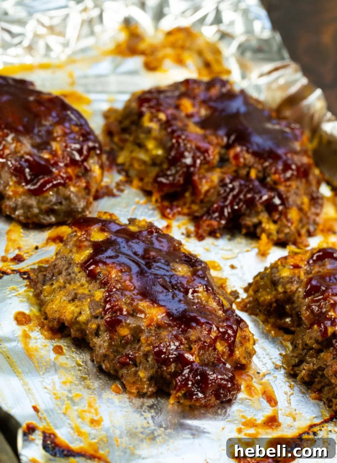 Delicious Mini BBQ Cheddar Meatloaves 3 Mini BBQ Cheddar Meatloaves arranged neatly on a baking sheet, ready for the oven.