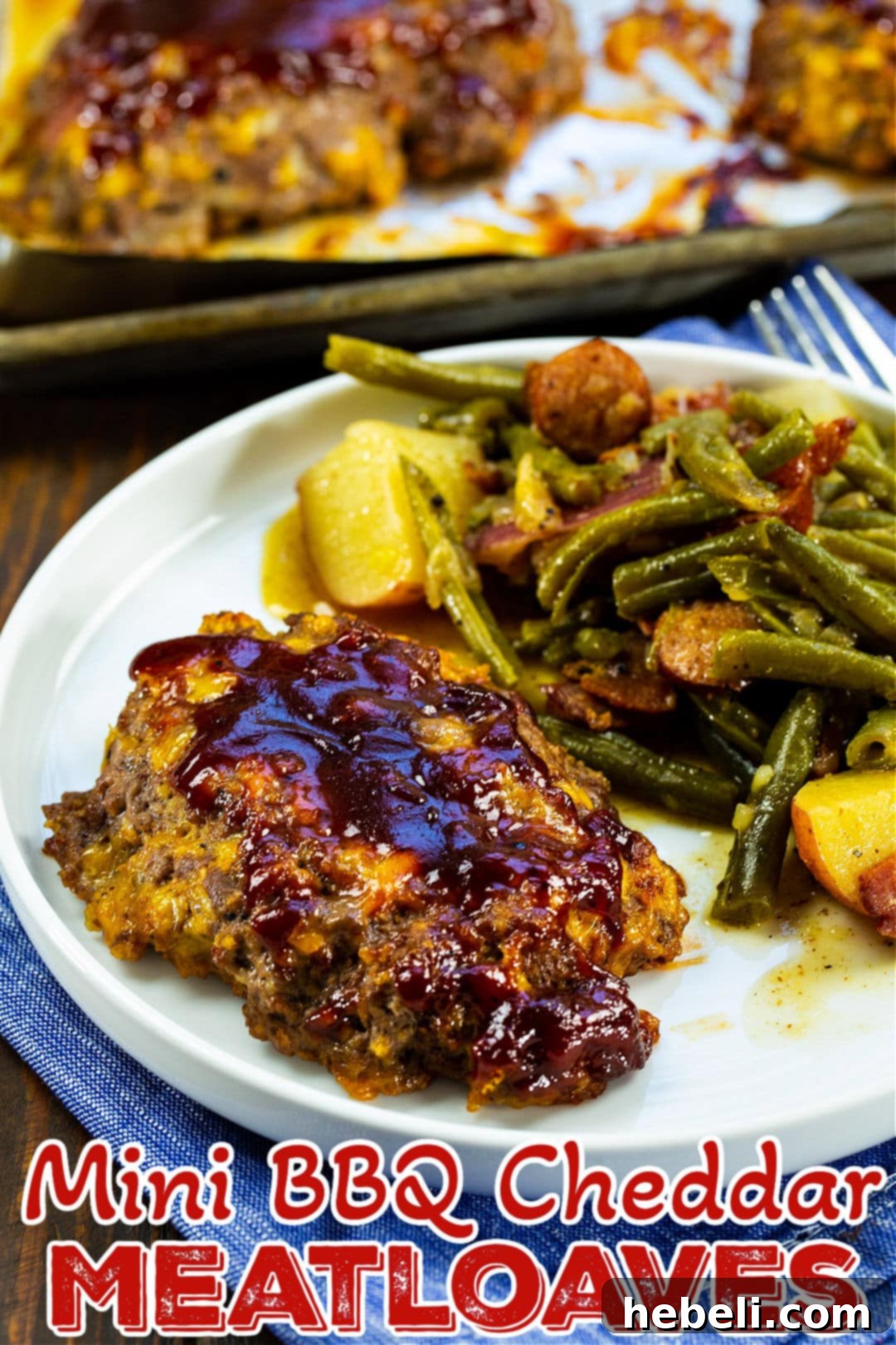 Delicious Mini BBQ Cheddar Meatloaves 4 Close-up shot of a Mini BBQ Cheddar Meatloaf on a plate with green beans, highlighting its delicious glaze.