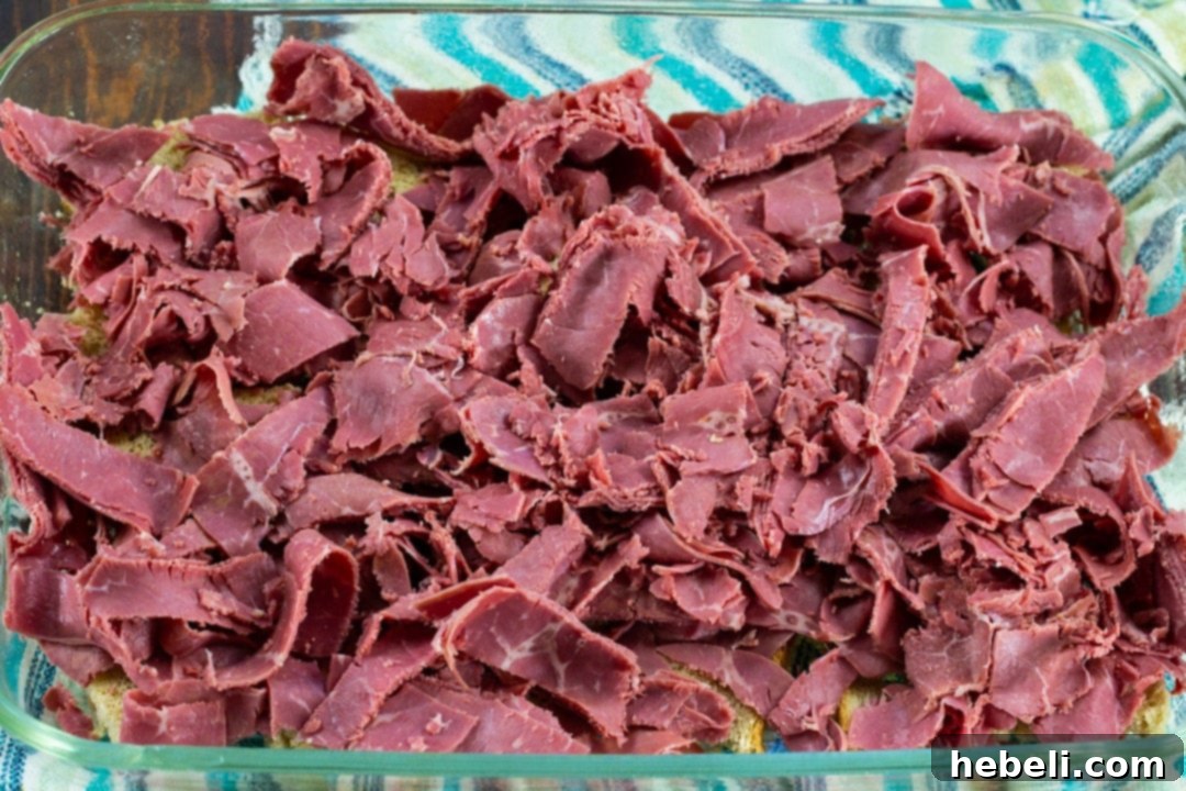 The Ultimate Reuben Casserole 5 Strips of corned beef arranged on top of the bread cubes in the baking dish.