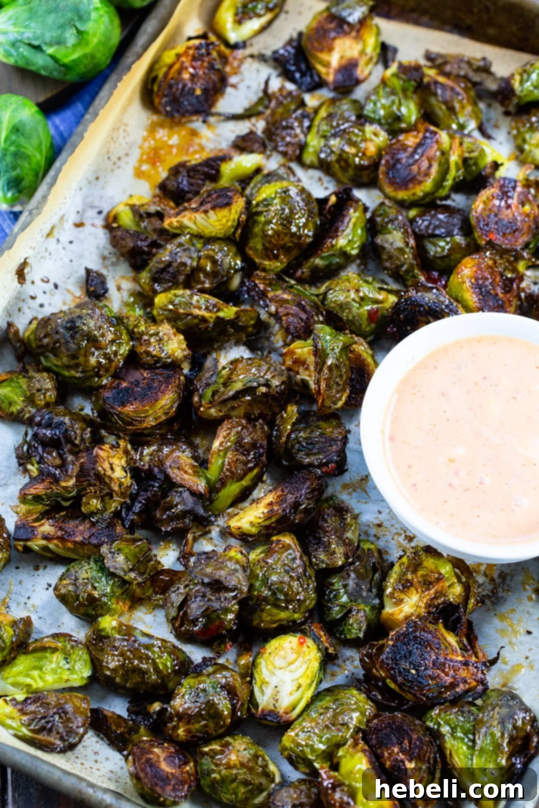 Raw Brussels Sprouts halved and seasoned on a baking sheet, ready for roasting.