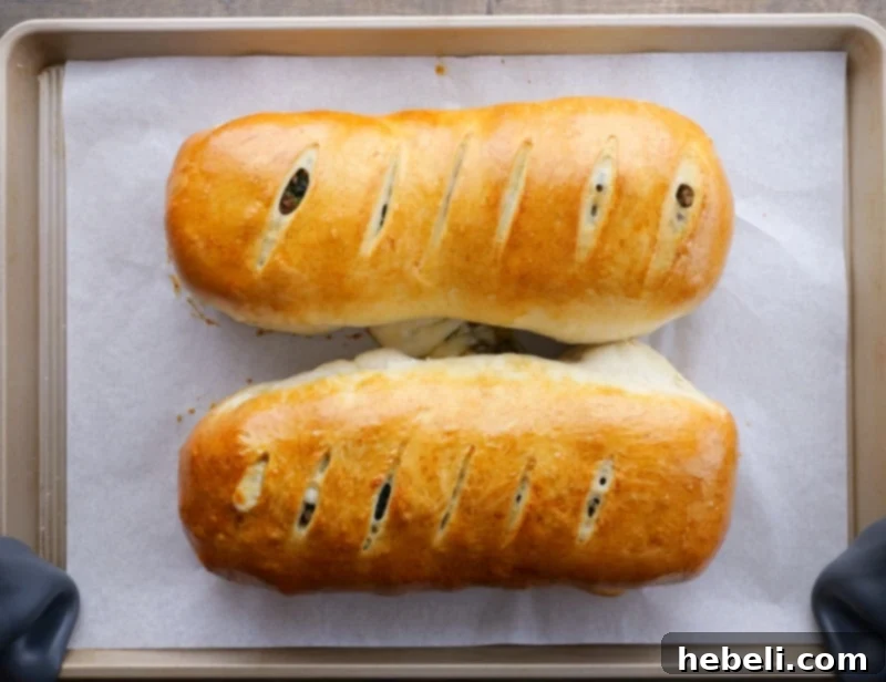 Savory Sausage and Spinach Swirl 11 Two freshly baked, golden-brown loaves of Sausage Spinach Bread on a baking sheet, ready to serve.