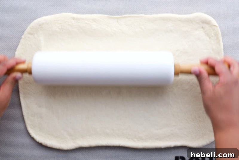 Savory Sausage and Spinach Swirl 6 Rolling out bread dough with a rolling pin on a lightly floured surface.