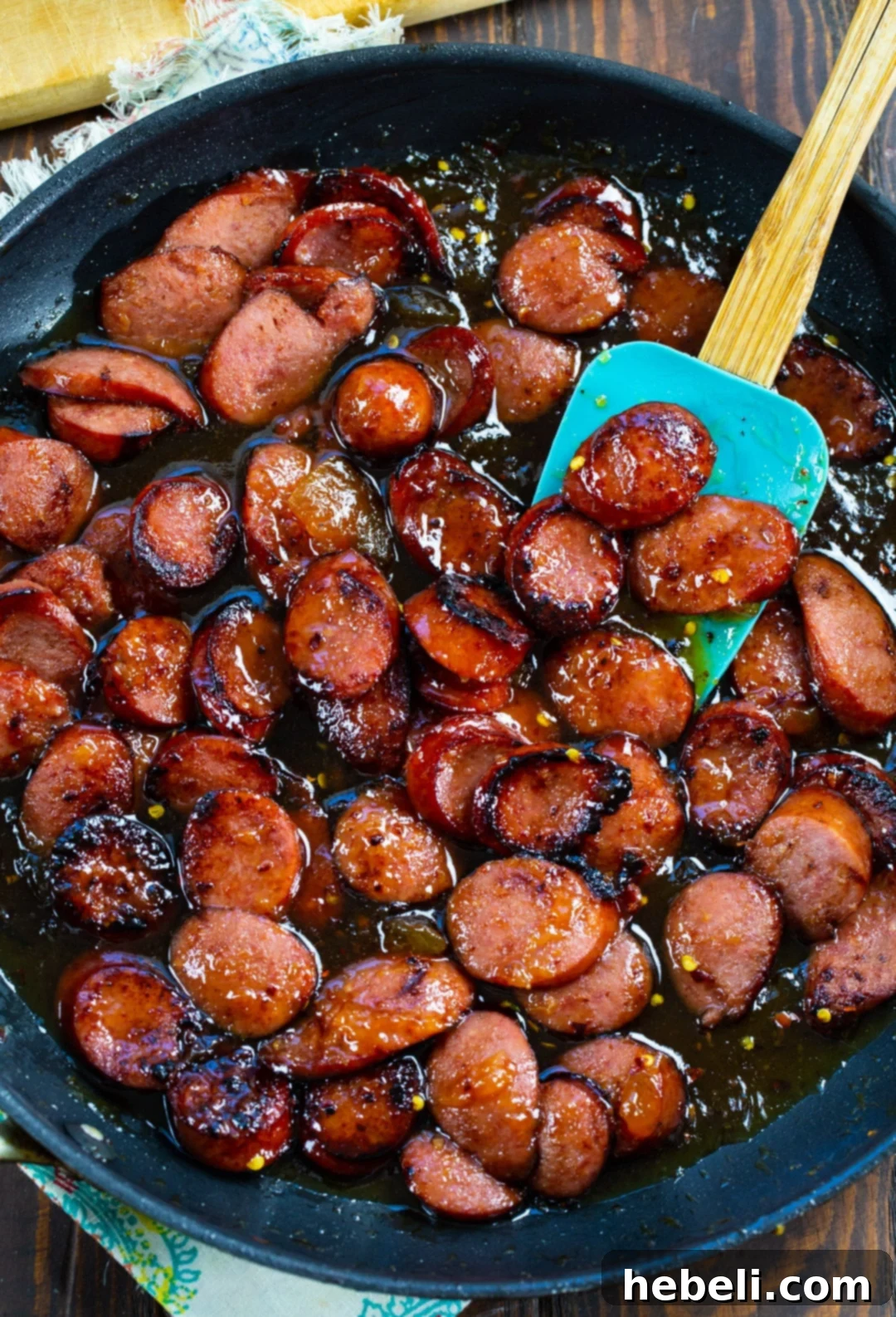 Spicy Peach Glazed Kielbasa browning and sizzling in a nonstick skillet.