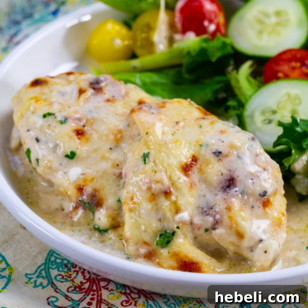 Baked Caesar Chicken on plate with salad.