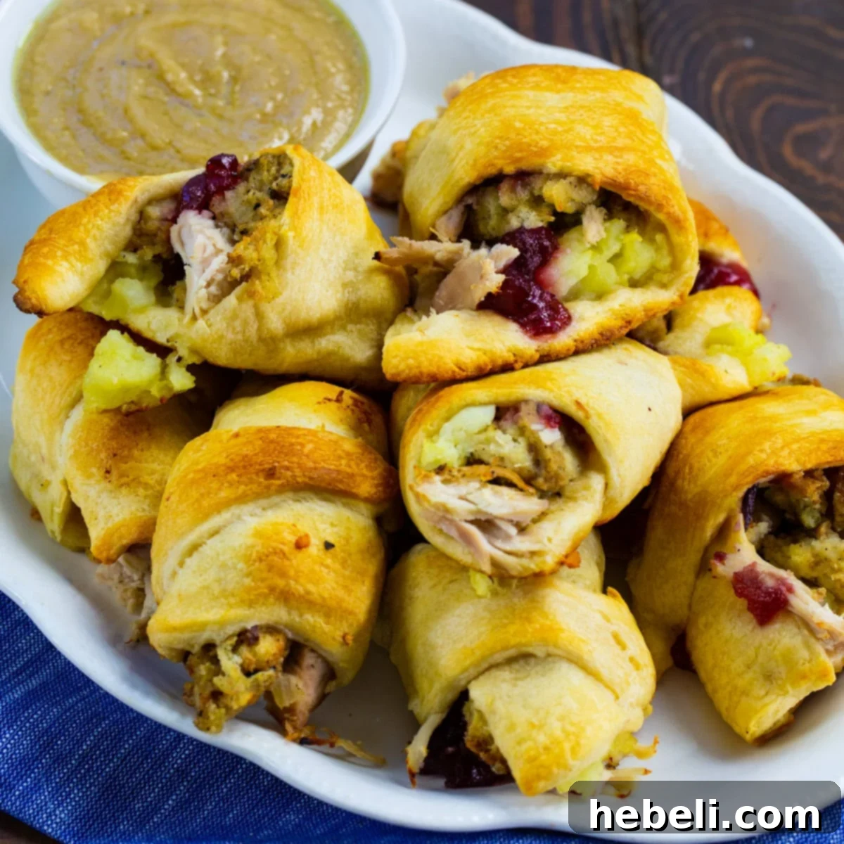 Delicious Thanksgiving Crescent Rolls 2 Golden-baked Thanksgiving Crescent Rolls arranged neatly on a plate, with a small bowl of savory brown gravy ready for dipping.