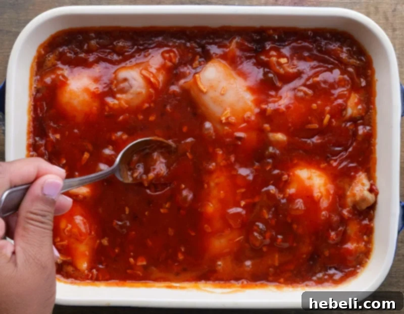 A cook spooning the apricot glaze over baking chicken thighs for extra moisture and flavor.