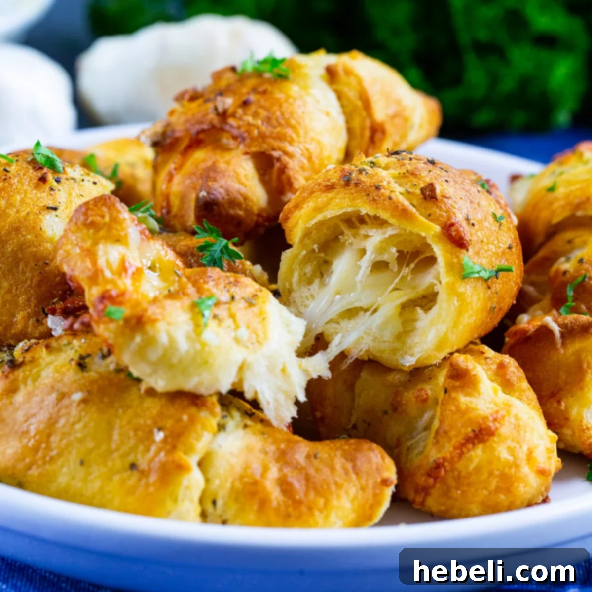 Golden brown Air Fryer Cheesy Garlic Crescent Rolls with one roll cut open to reveal melted cheese inside, served on a plate.