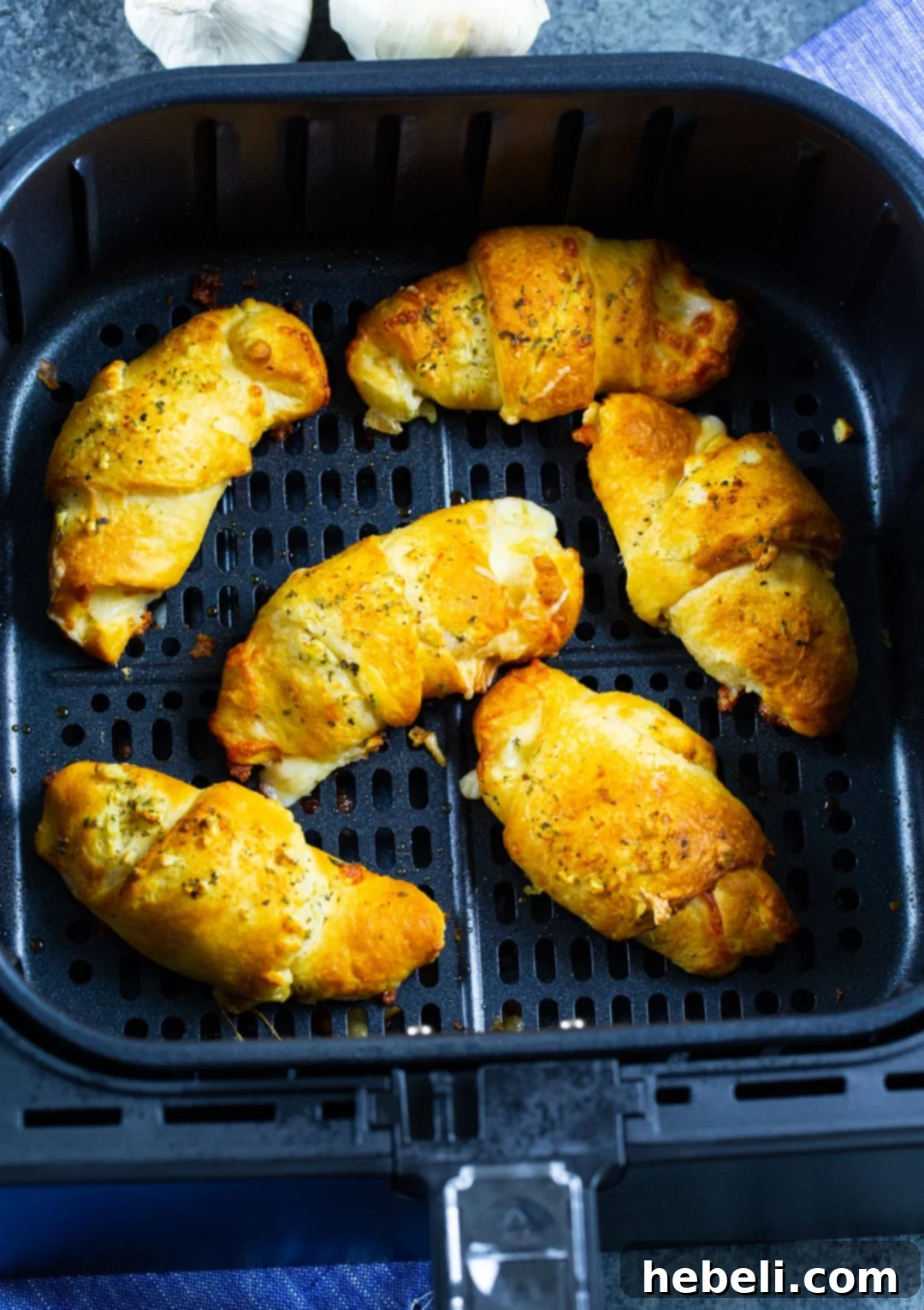 Cheesy Garlic Crescent Rolls baking inside an air fryer basket, turning golden brown.