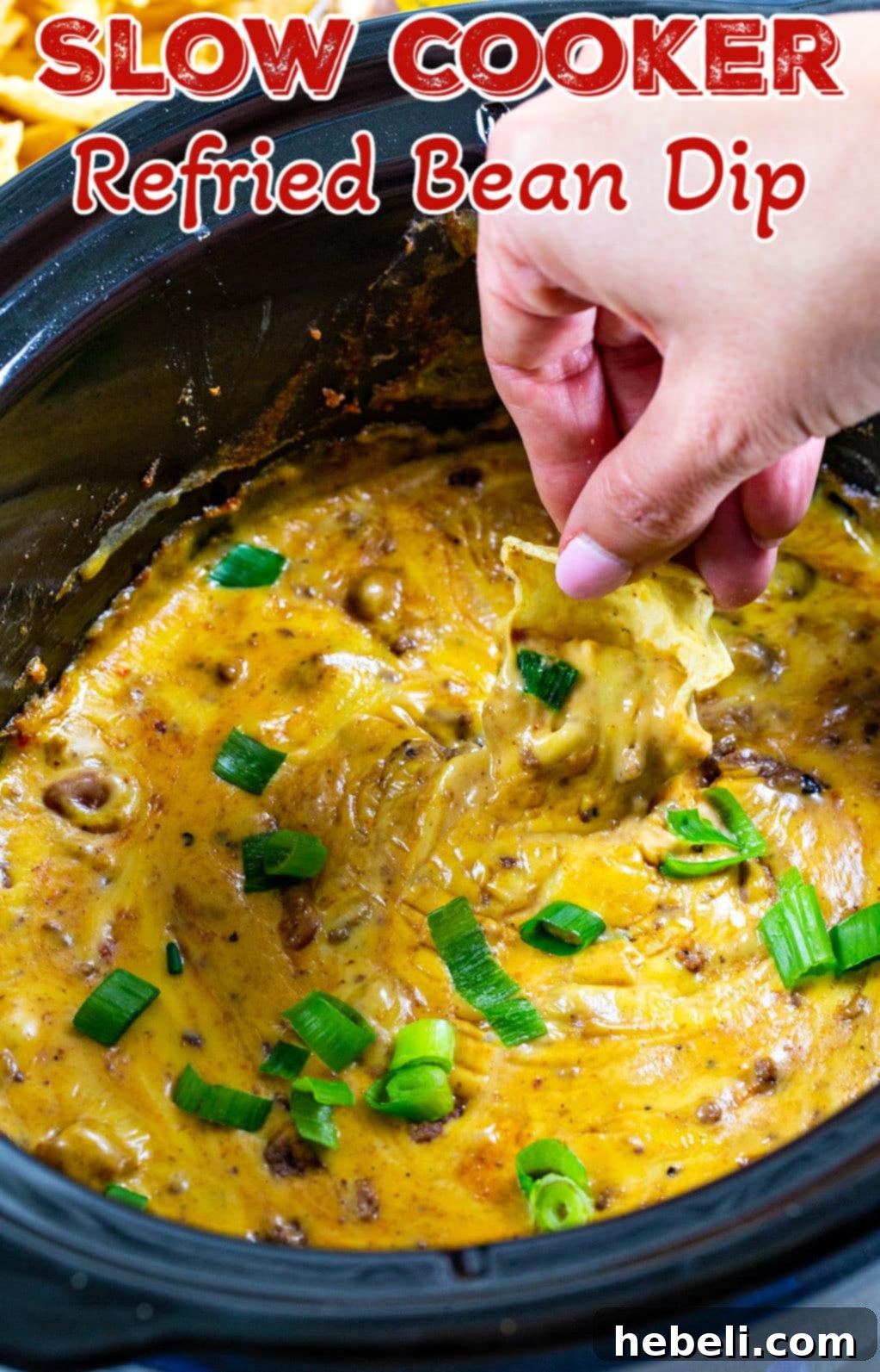 Chip scooping up Refried Bean Dip out of slow cooker.