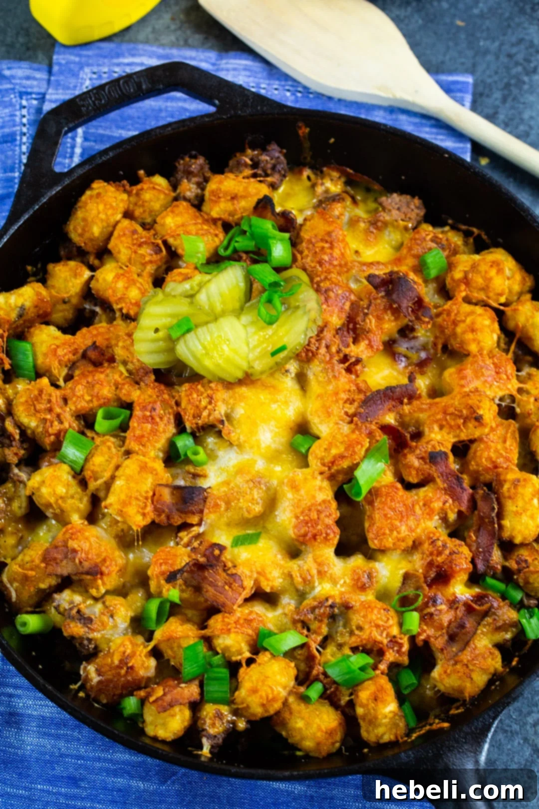 Close-up of Cheeseburger Casserole in a cast iron pan, showing the golden tater tots and melted cheese.