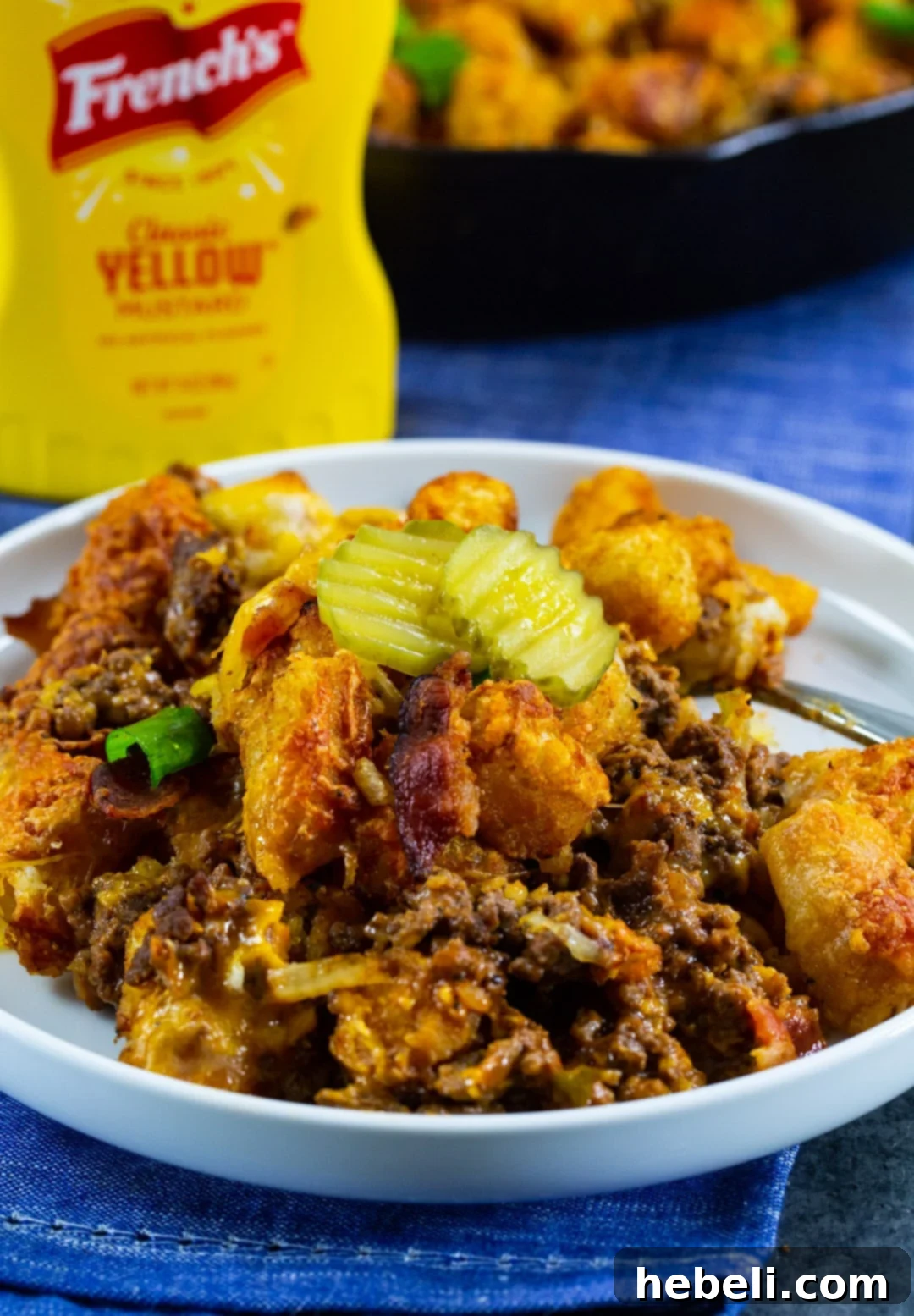 Cheeseburger Tater Tot Casserole dished up on a white plate with a fork.