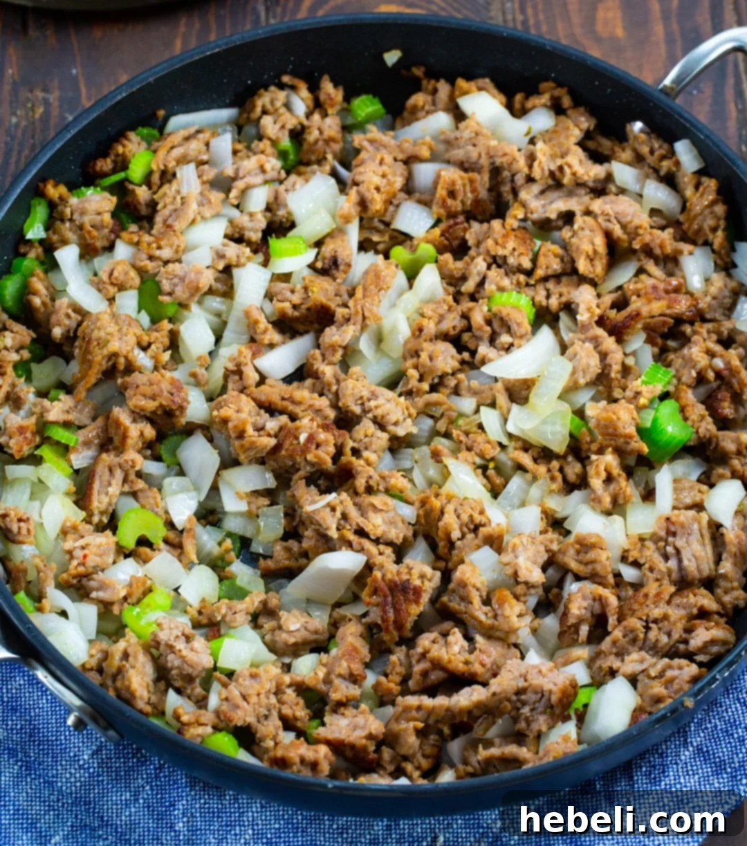 Sausage, onion, and celery cooking in a skillet before going into the slow cooker.