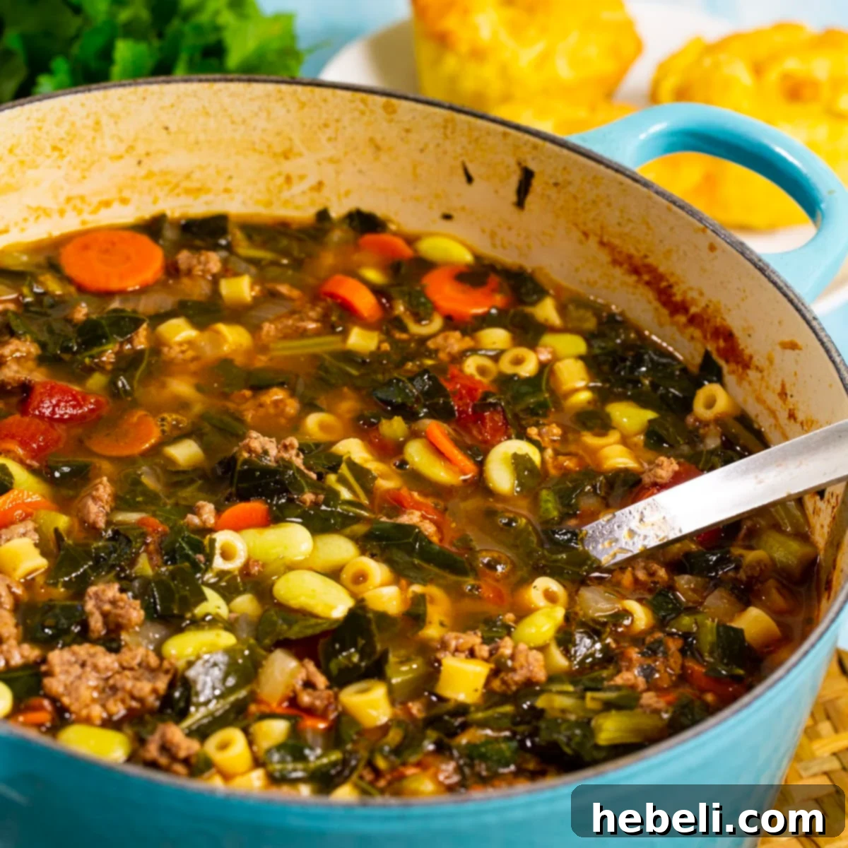 A large Dutch oven filled with steaming Southern Minestrone, showcasing a rich broth, ground beef, and green vegetables.
