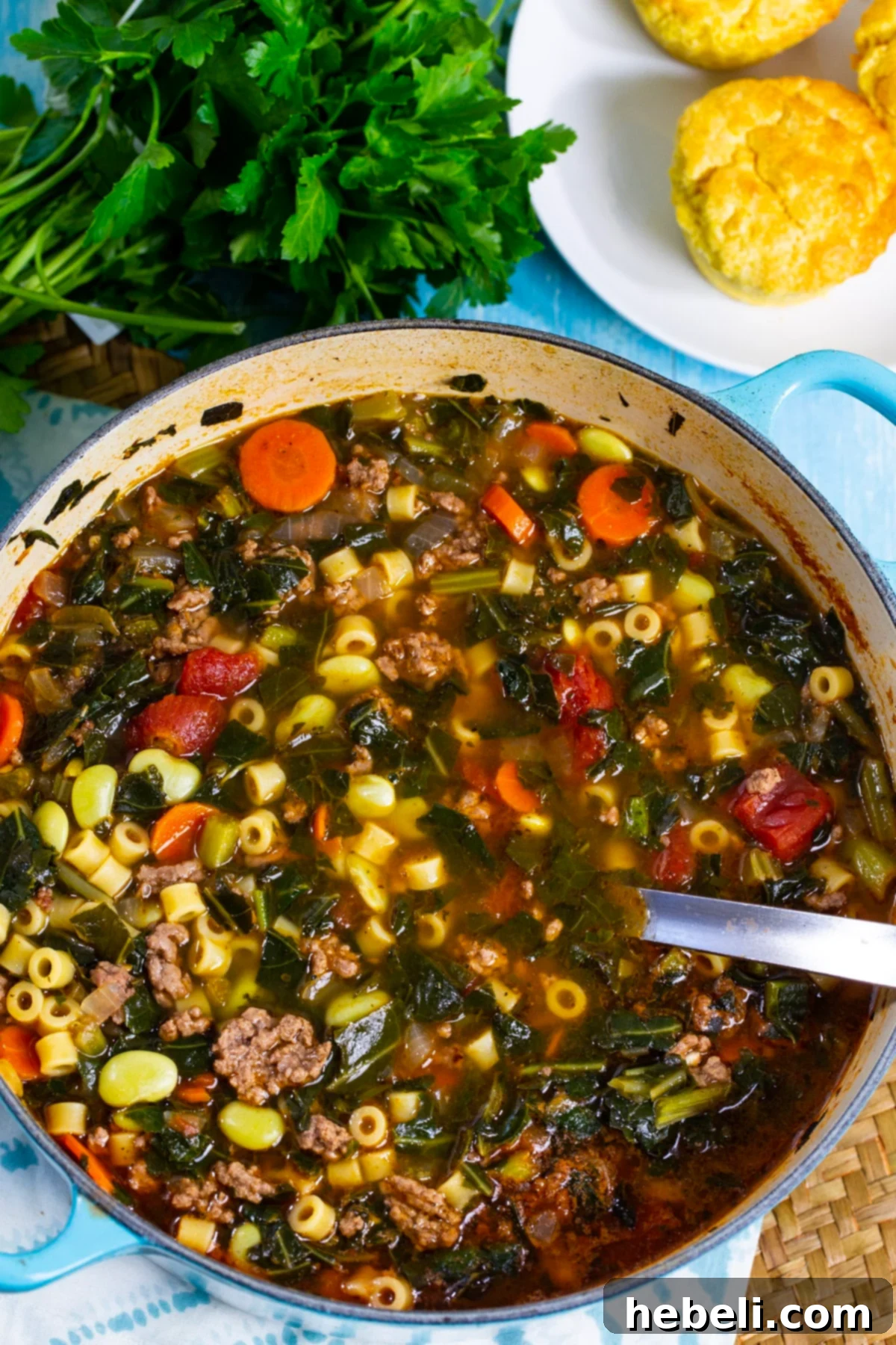 Close-up of Southern Minestrone simmering in a large Dutch oven, showing the rich texture of ground beef, lima beans, and collard greens.