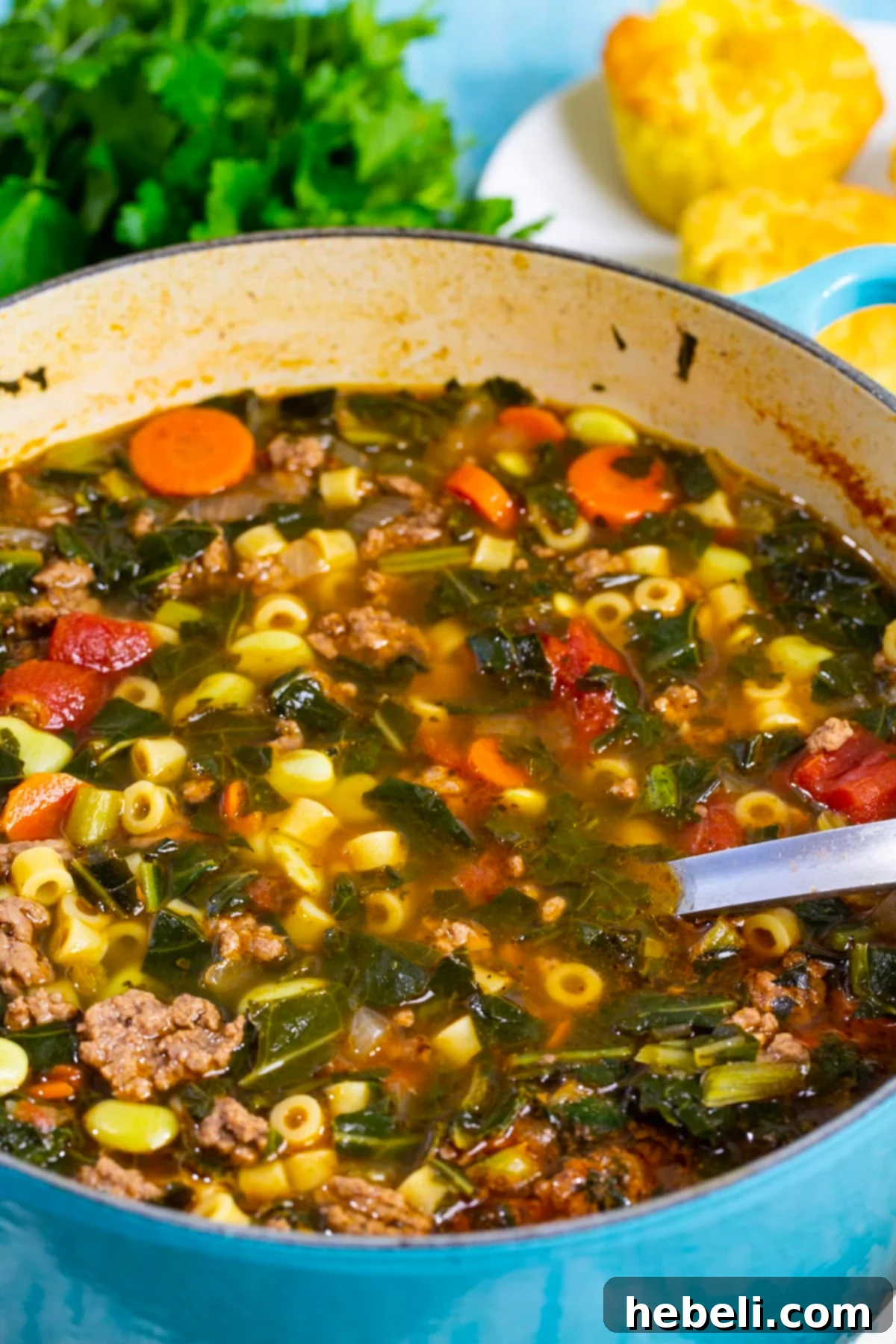 A close-up view of the Southern Minestrone in a Dutch oven, highlighting the robust ingredients like ground beef, vibrant collard greens, and creamy lima beans.