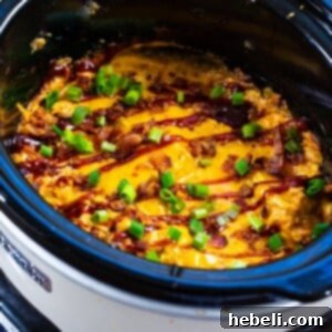Close-up of Slow Cooker BBQ Chicken Dip with a chip scooping it up.