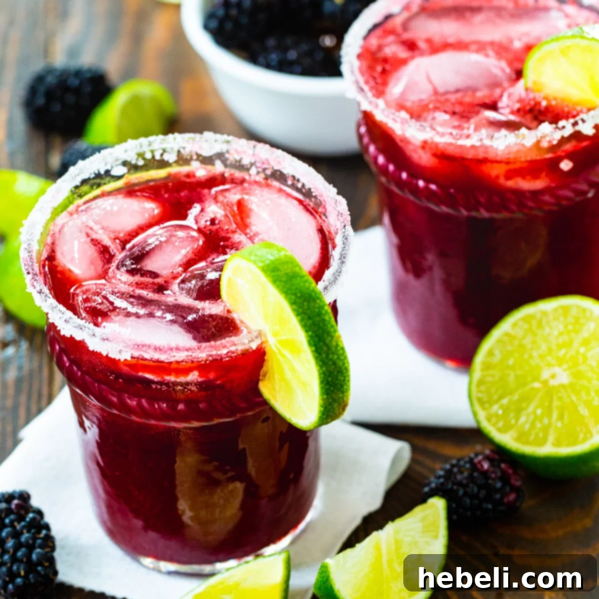 Two glasses of vibrant Blackberry Margaritas, garnished with fresh blackberries and lime wedges.