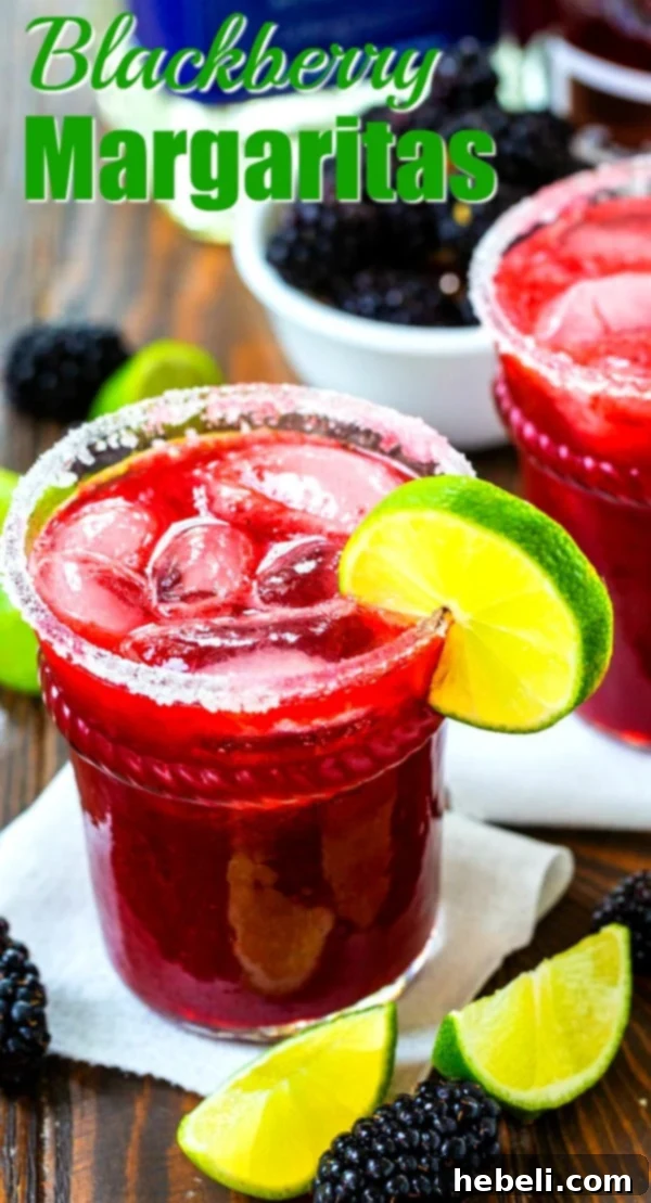 A Blackberry Margarita in a tall glass, garnished with lime wedges and fresh blackberries.