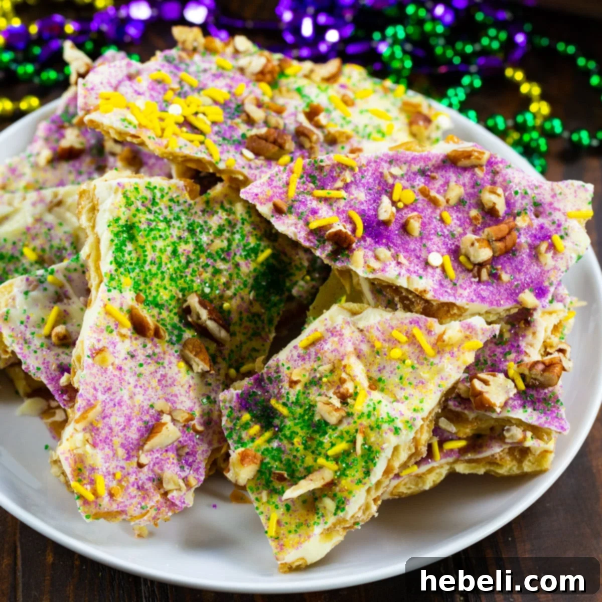 King Cake Toffee Bark 2 King Cake Cracker Candy on a festive plate, decorated with purple, green, and gold sprinkles.