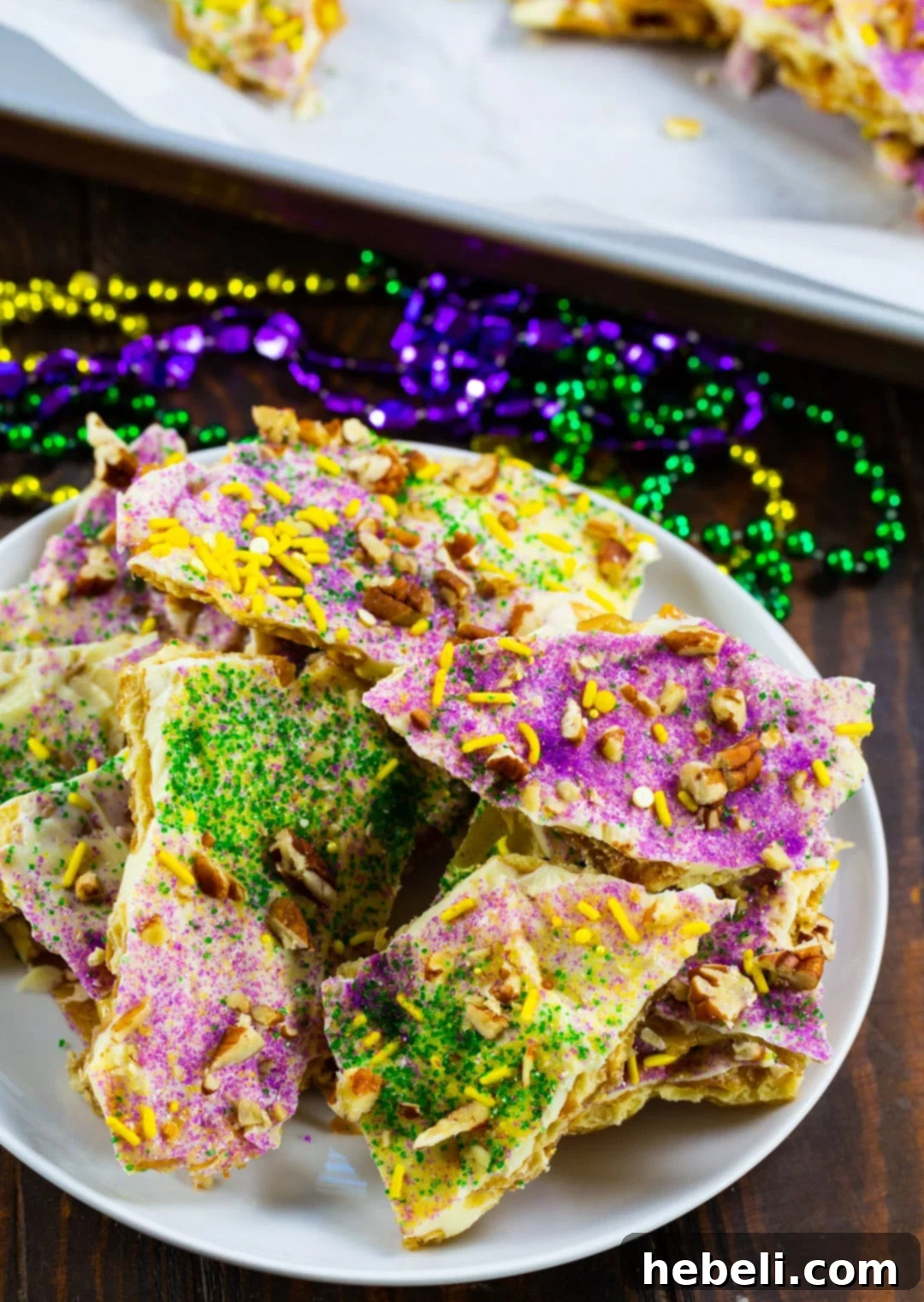 King Cake Toffee Bark 4 King Cake Cracker Candy pieces arranged on a white plate, showcasing the colorful sprinkles.