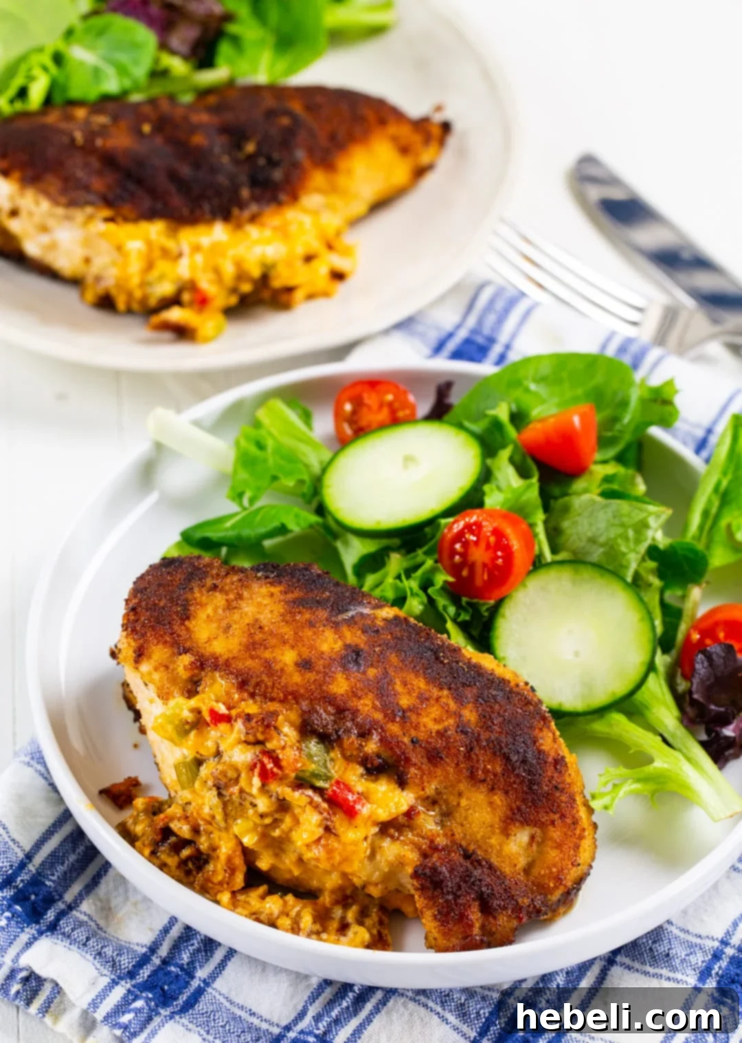 Creamy Pimento Cheese Stuffed Chicken 3 Close-up of a cooked Stuffed Chicken Breast on a plate with fresh greens, showing the cheese filling peeking out.