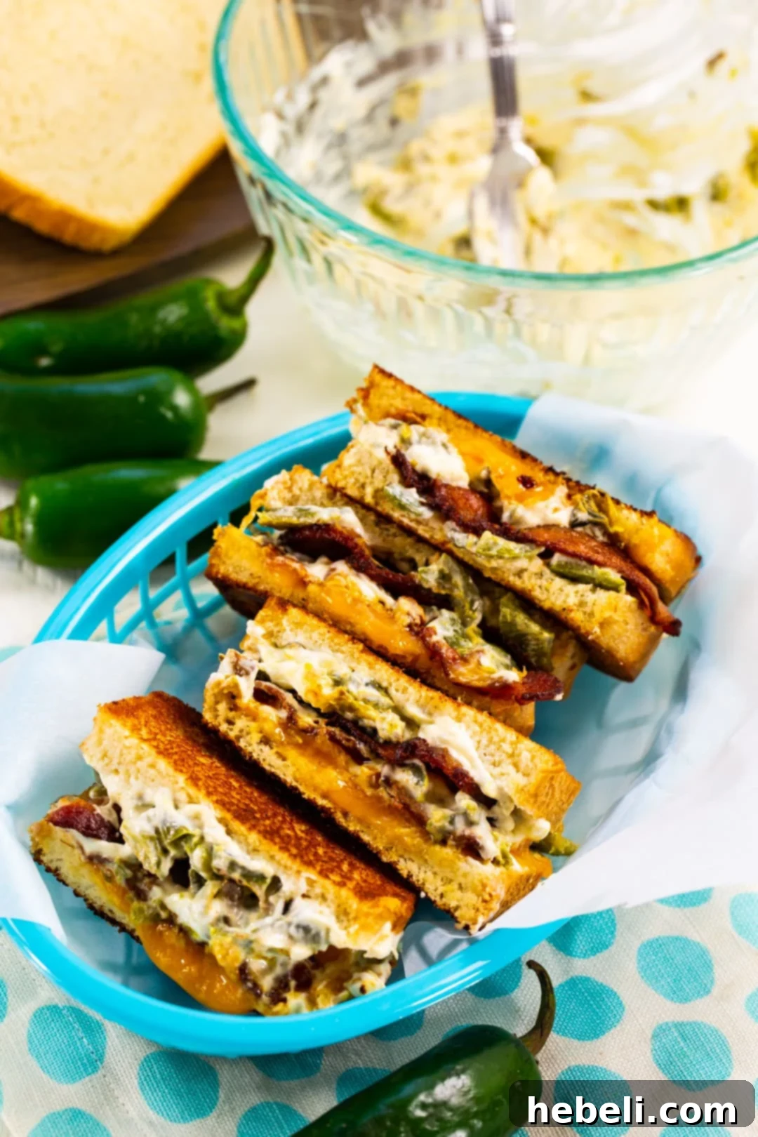 Four halves of the Jalapeno Popper Grilled Cheese, cut diagonally and neatly arranged in a rustic basket, showcasing the melted cheese and crispy exterior.
