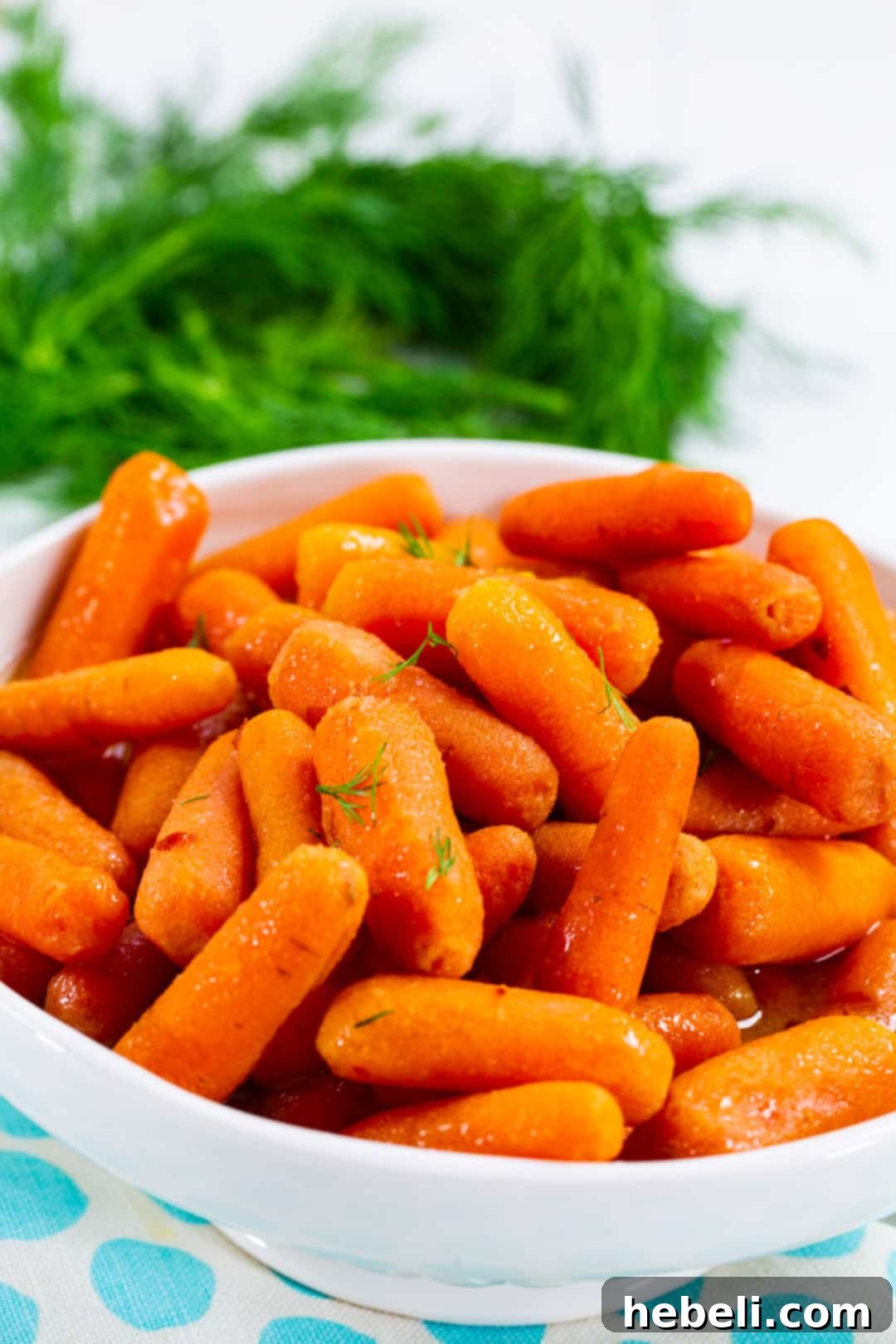Slow Cooker Baby Carrots served in a white bowl, garnished with fresh dill.