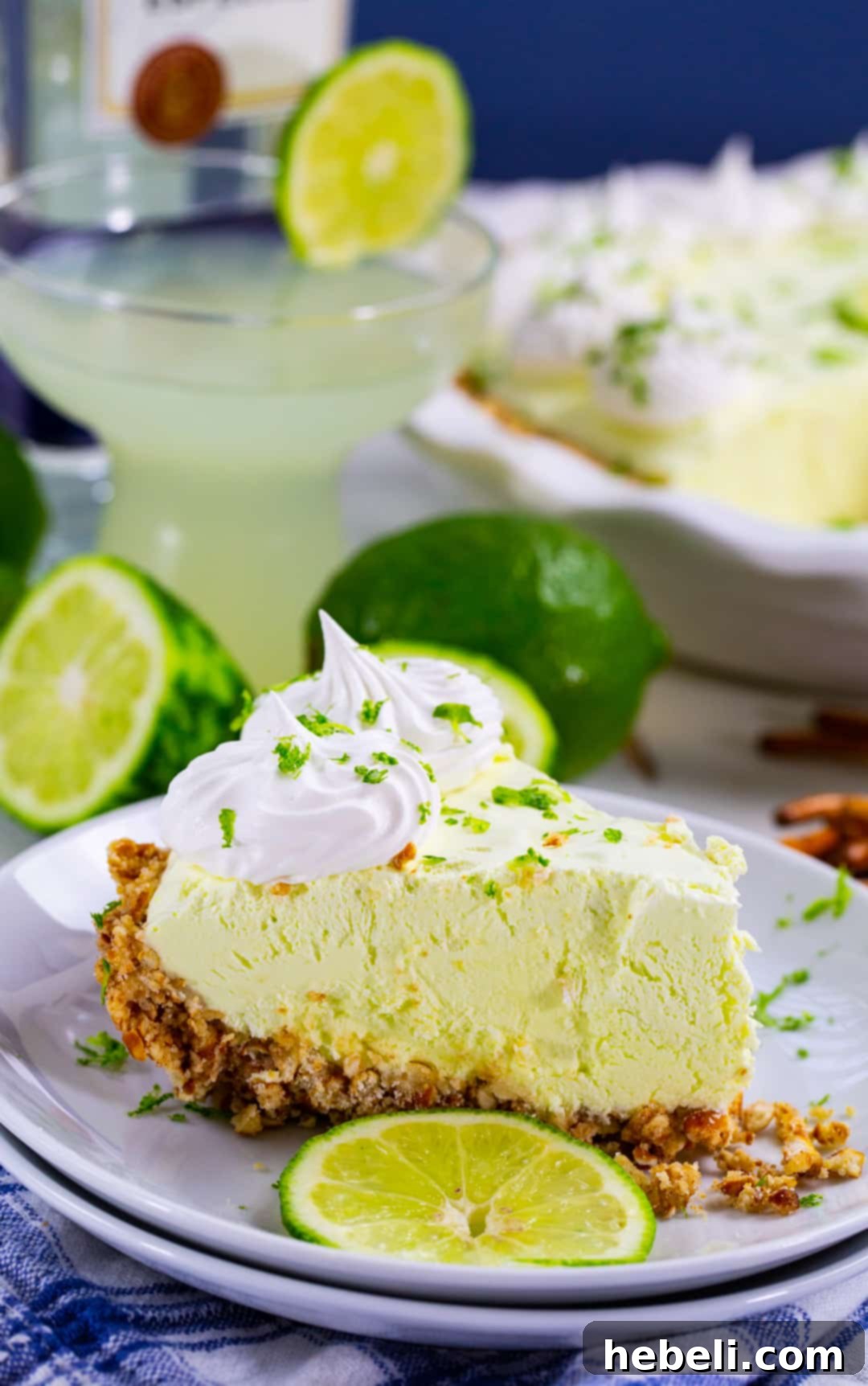 Effortless Margarita Dream Pie 5 A delectable slice of No-Bake Margarita Pie, garnished with a lime wedge, resting on a white plate.