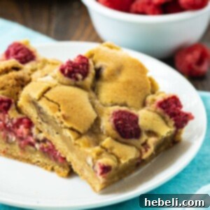 Two Raspberry Bars on a white plate, showcasing their inviting texture and fresh topping.