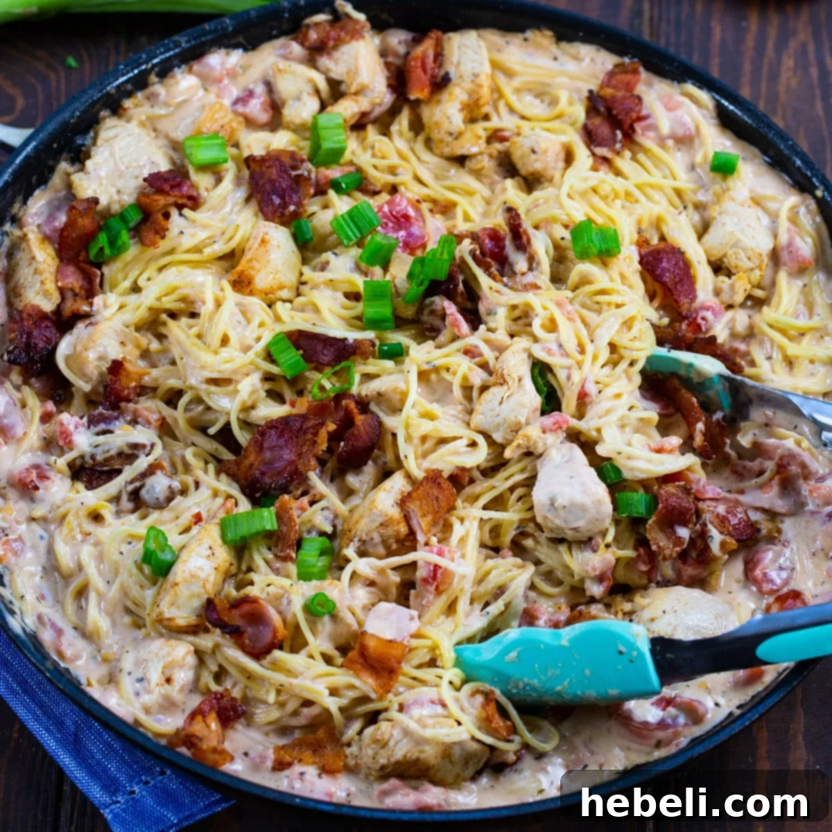 Creamy Angel Hair Pasta with Bacon and Chicken simmering in a skillet, ready to be served.
