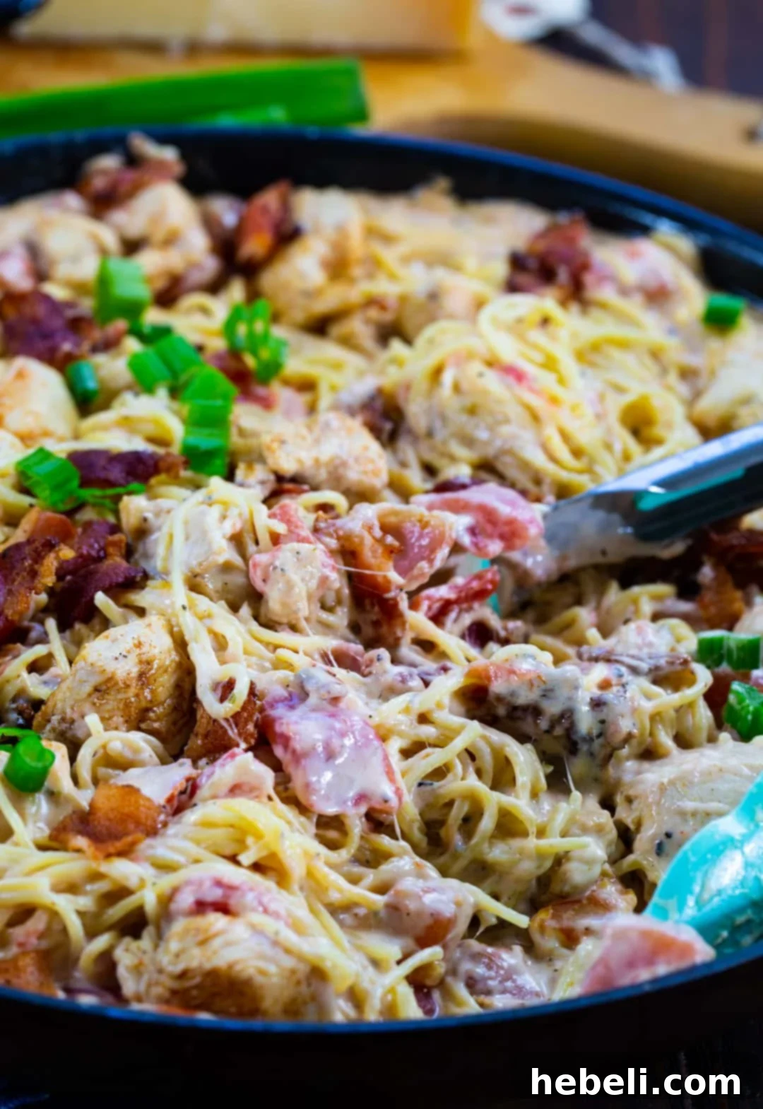 Close-up view of creamy angel hair pasta in a large skillet, highlighting its luscious texture and inviting warmth.
