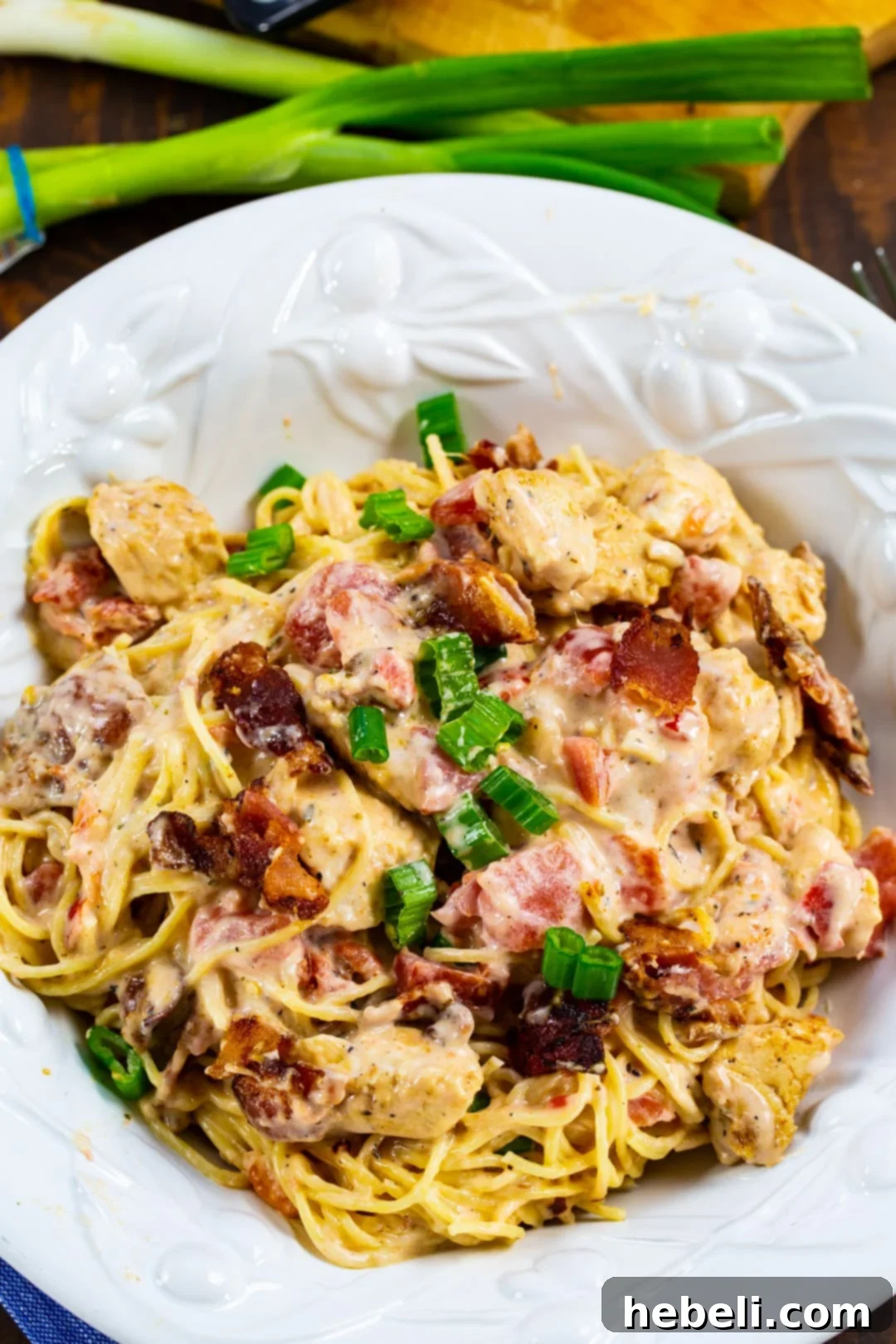 Creamy Angel Hair Pasta with Chicken and Bacon in a white serving bowl, garnished with fresh green onions.