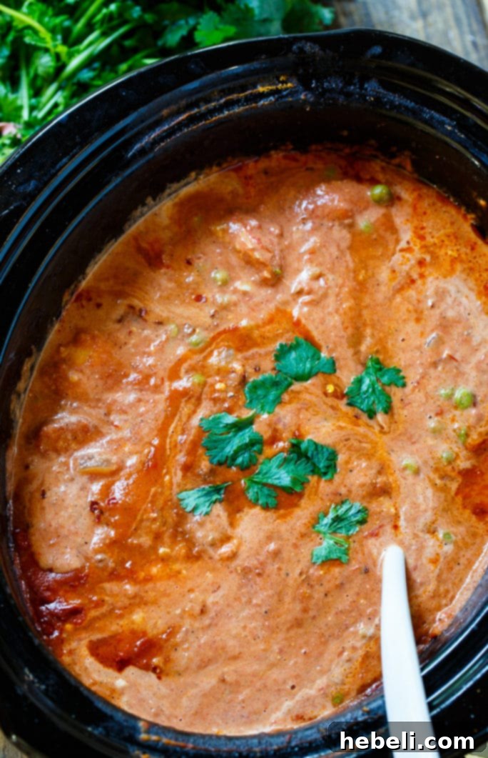 Effortless Slow Cooker Chicken Tikka 2 Tikka Masala simmering in a black slow cooker, showcasing its rich color and texture.