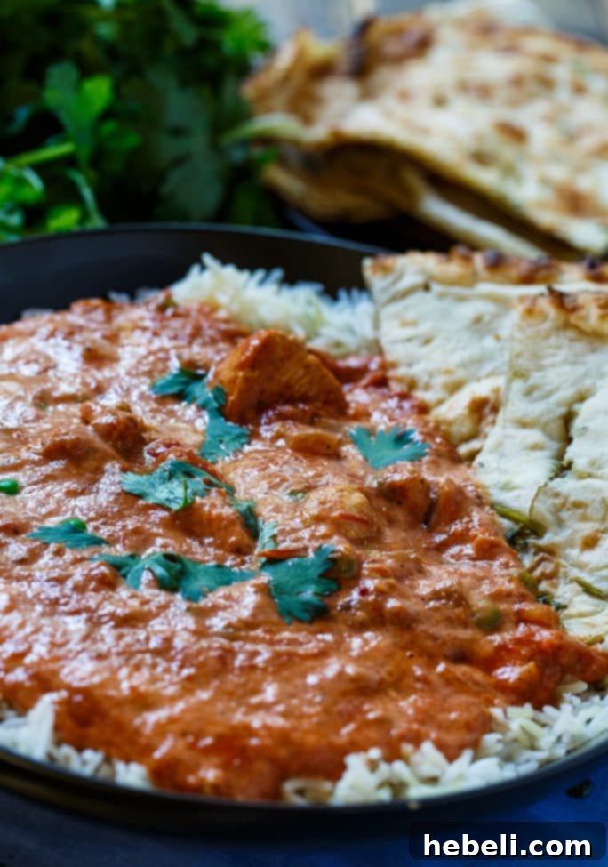 Effortless Slow Cooker Chicken Tikka 4 A hearty serving of Slow Cooker Chicken Tikka Masala with rice, naan bread, and fresh cilantro, ready to be enjoyed.