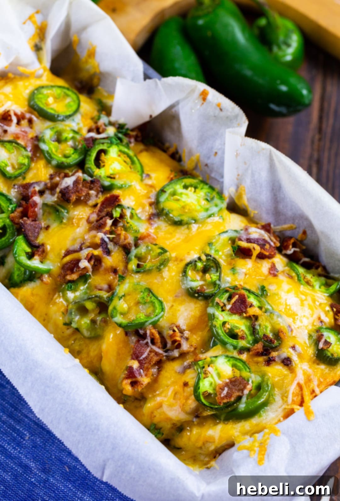 Spicy Cheesy Pull-Apart Perfection 3 Close-up of golden brown pull-apart bread in a loaf pan, showing layers of cheese and jalapenos.
