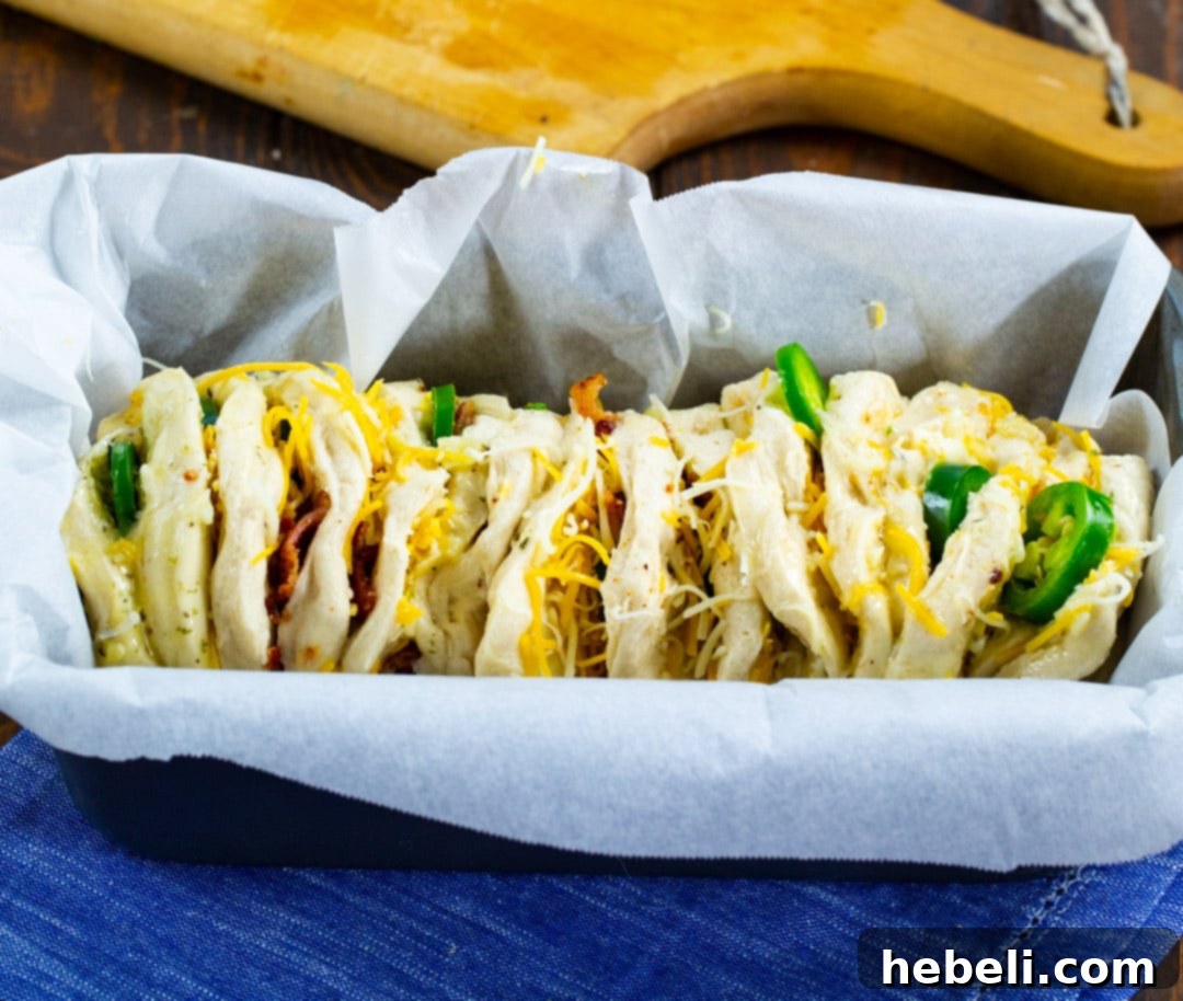 Spicy Cheesy Pull-Apart Perfection 5 Uncooked pull-apart bread dough arranged sideways in a parchment-lined loaf pan.