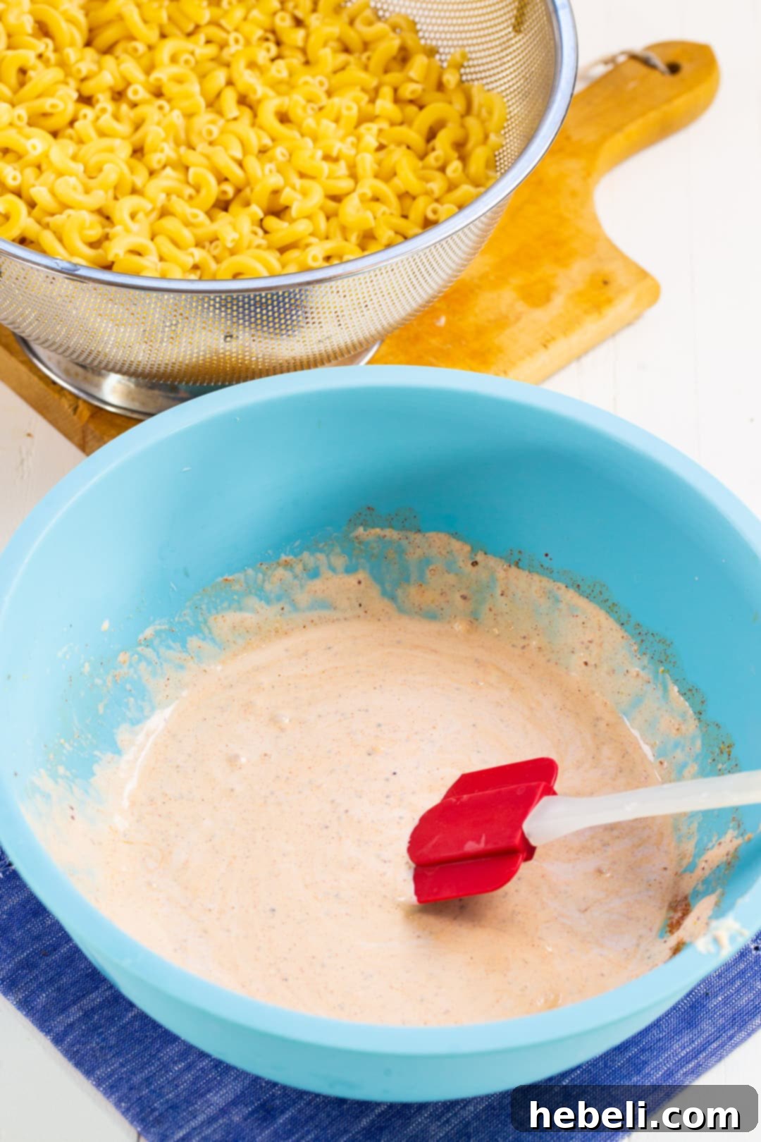 Kickin' Cajun Macaroni Salad 3 Rich and creamy dressing for Cajun macaroni salad in a mixing bowl, showcasing its vibrant color.