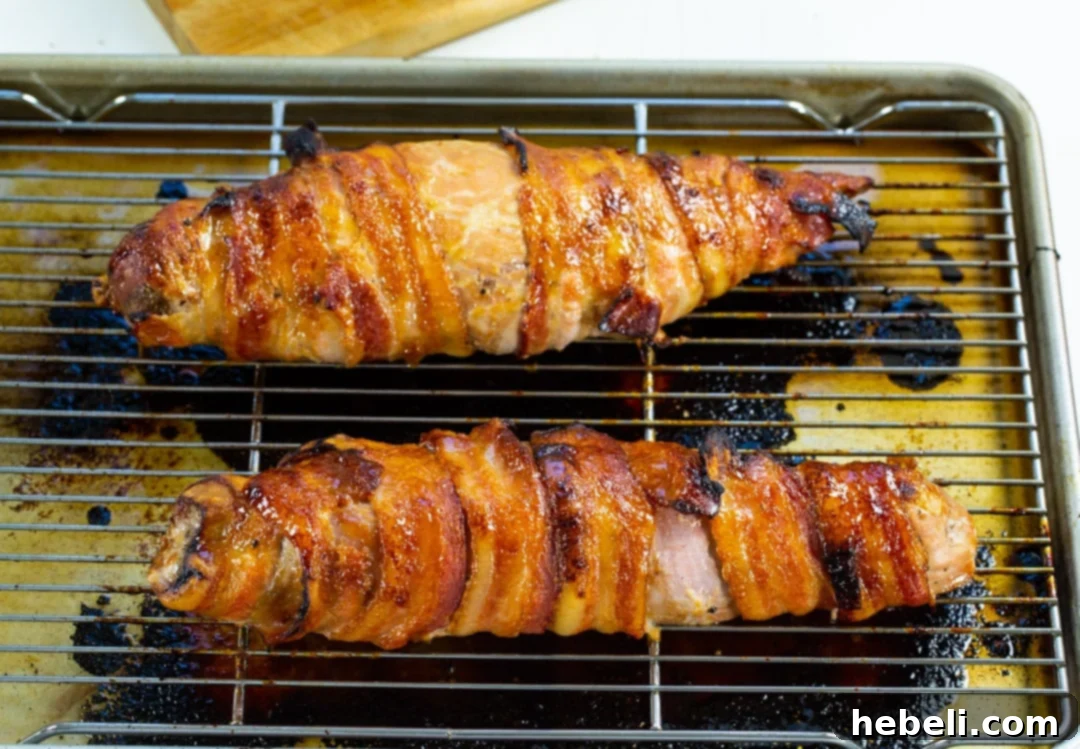 Cooked pork tenderloins resting on a baking sheet after being removed from the oven.