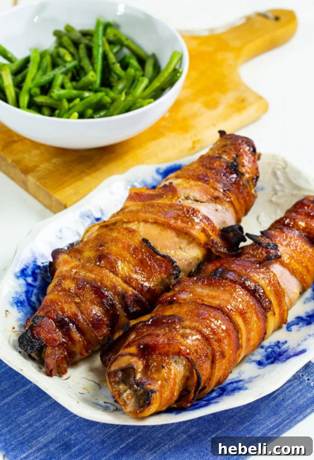 Beautifully sliced Brown Sugar Bacon Wrapped Pork Tenderloin served alongside fresh green beans.