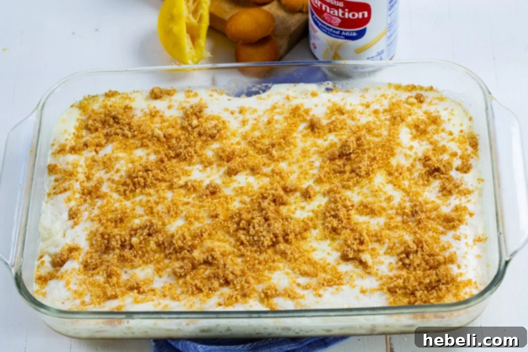 A large 9x13-inch baking dish filled with the prepared Lemon Fluff dessert, showcasing its smooth, light yellow surface ready to be chilled.