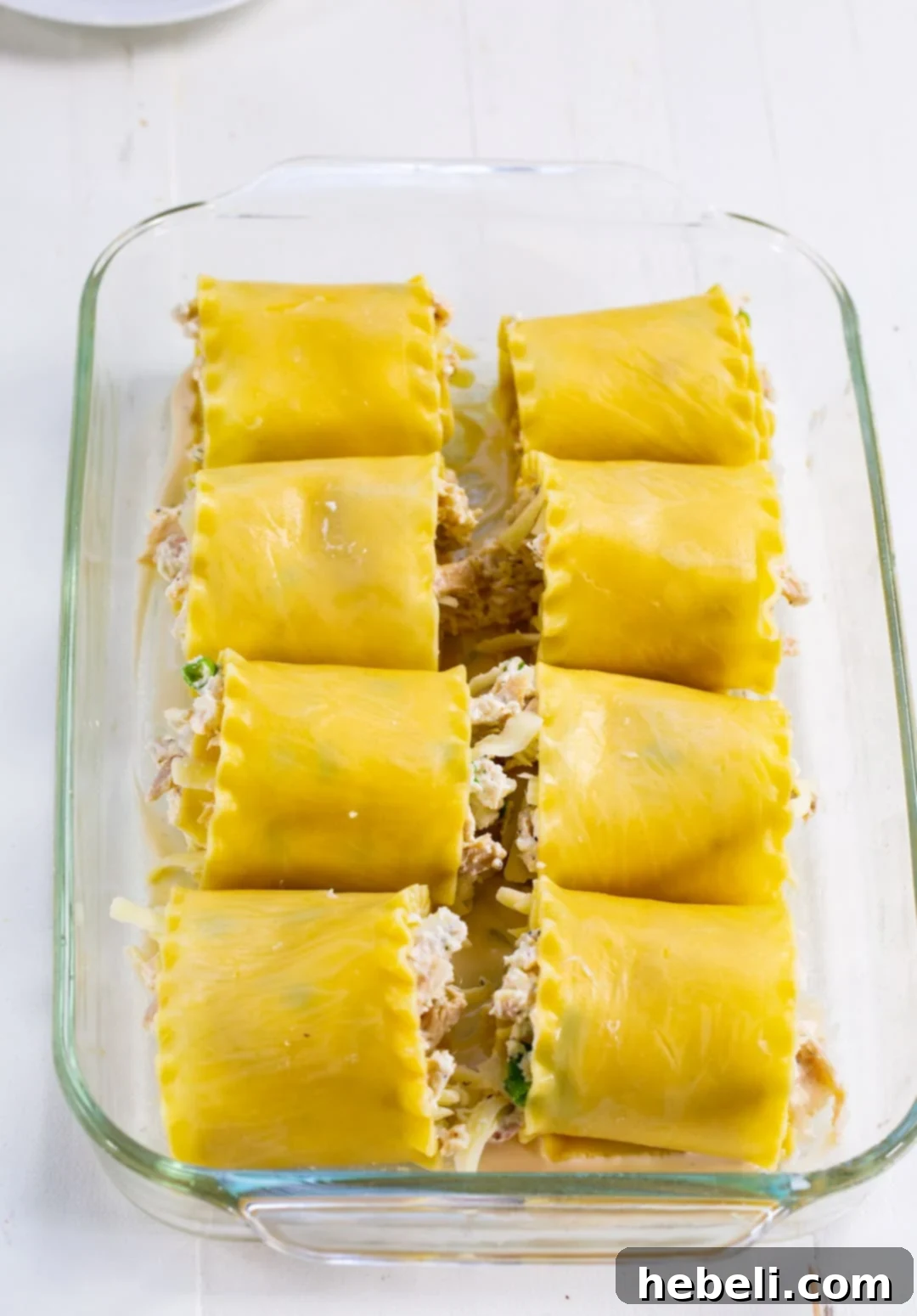 Alfredo Chicken Lasagna Pinwheels 5 Unbaked Chicken Alfredo Lasagna Roll-Ups neatly arranged in a baking dish, topped with sauce and cheese, ready for the oven.