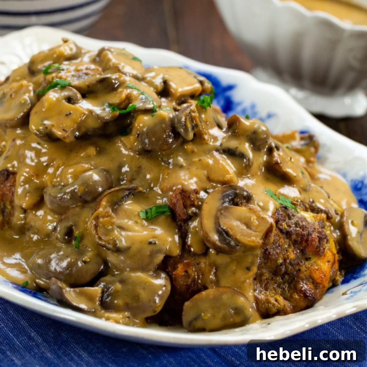 A perfectly sliced meatloaf topped generously with creamy mushroom gravy, presented on an elegant serving platter.