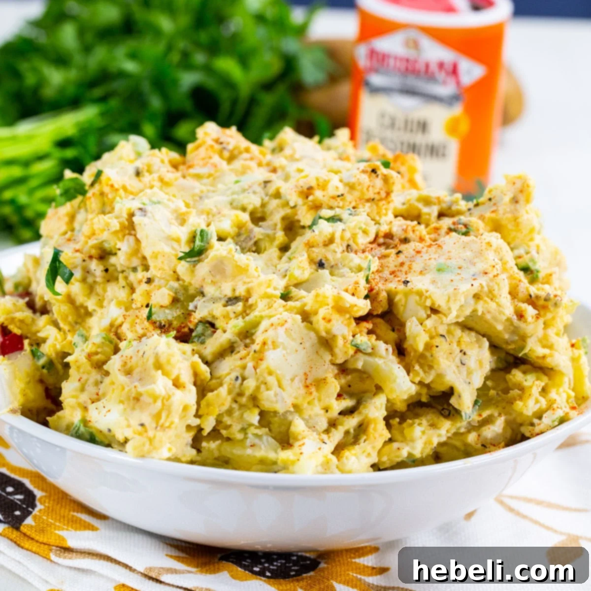 Cajun Kick Potato Salad 2 Cajun Potato Salad in a white serving bowl, garnished with paprika and parsley.
