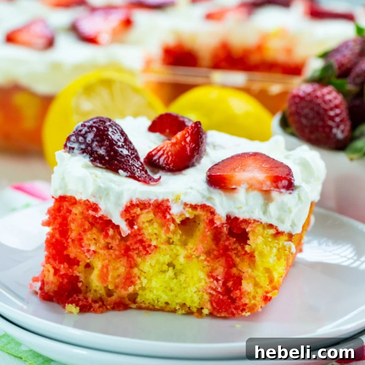 A beautifully plated slice of Strawberry Lemonade Poke Cake, showcasing its vibrant layers and fluffy frosting, ready to be enjoyed.