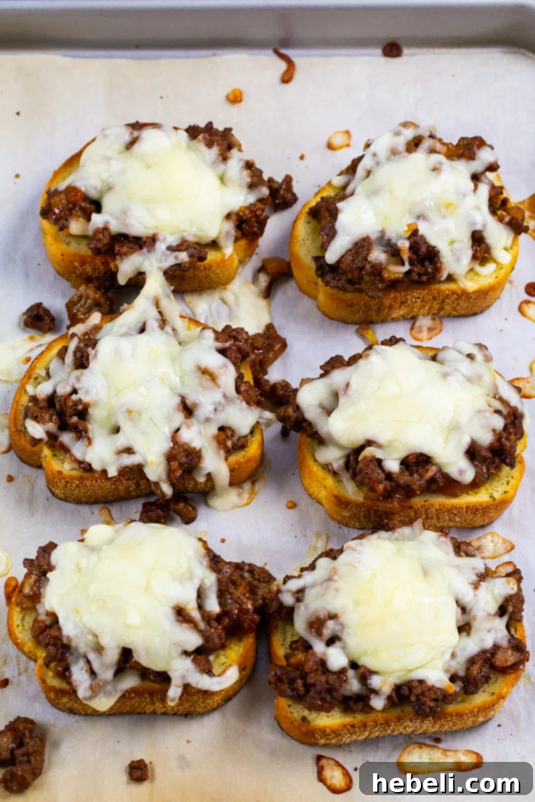 Loaded Texas Toast Sloppy Joes 3 Six pieces of Texas Toast covered with sloppy joe mixture and cheese on a baking sheet, ready for the oven.