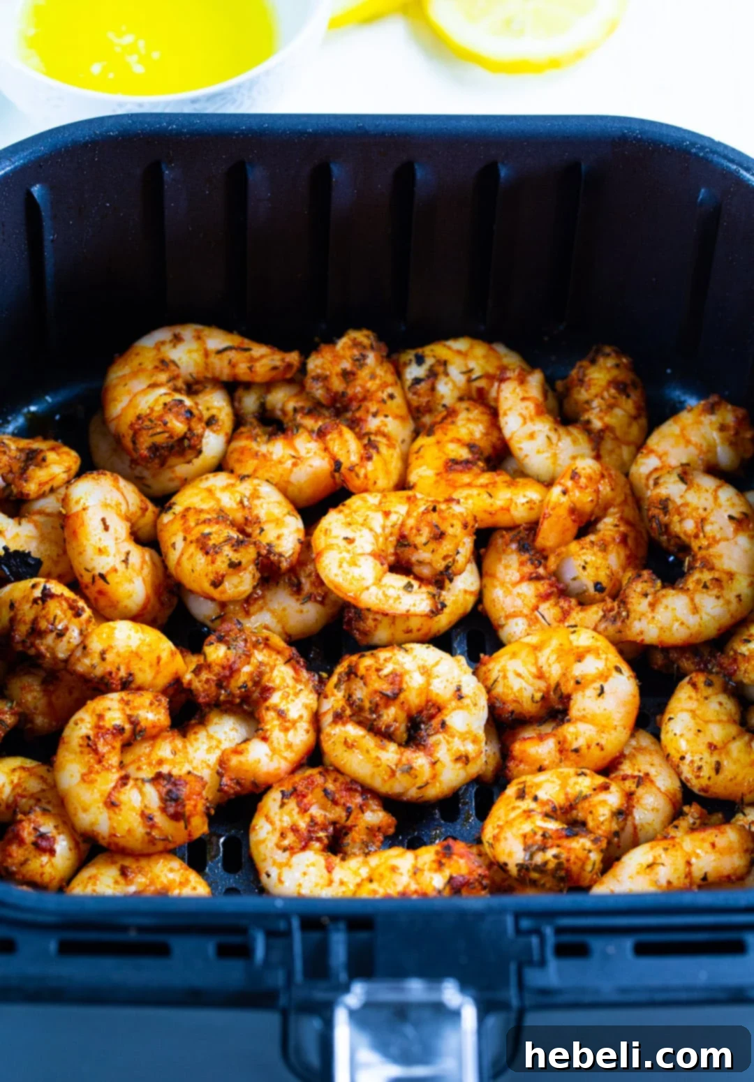 Cooked Cajun shrimp resting in an air fryer basket after cooking.