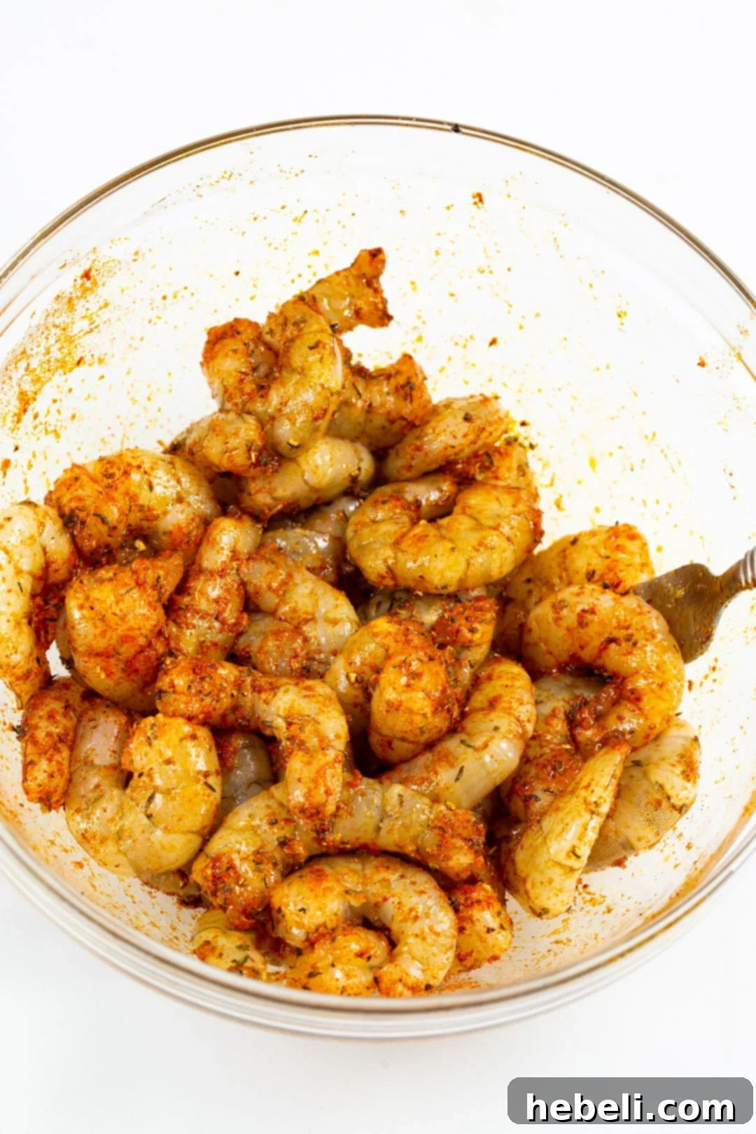 Raw shrimp meticulously coated in a vibrant Cajun seasoning blend, ready for air frying.